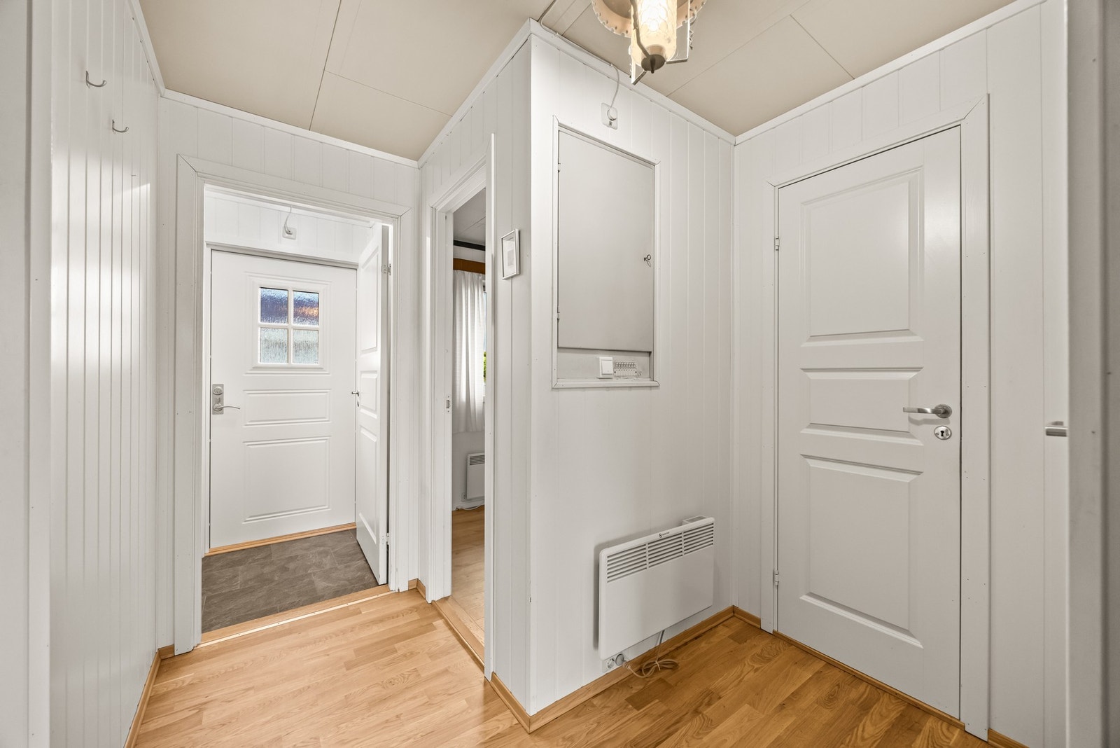Du kommer inn i boligen via vindfanget som har hvitmalte vegger og gulvbelegg. Galleribilde