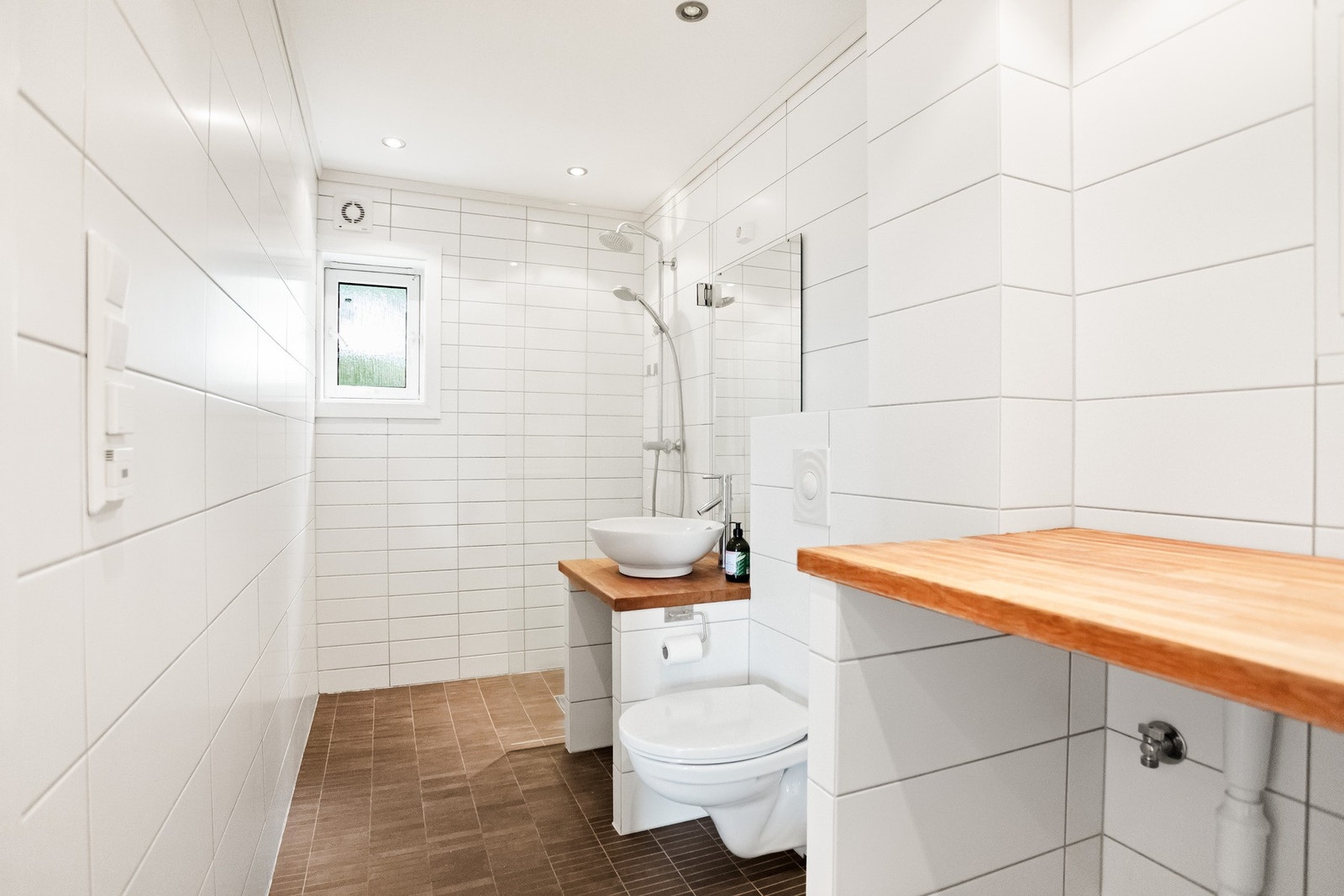 Baet er flislagt og har varmekabler i gulv. Badet er utstyrt med dusjhjørne, veggmontert WC, servant med speil, og opplegg for vaskemaskin Galleribilde