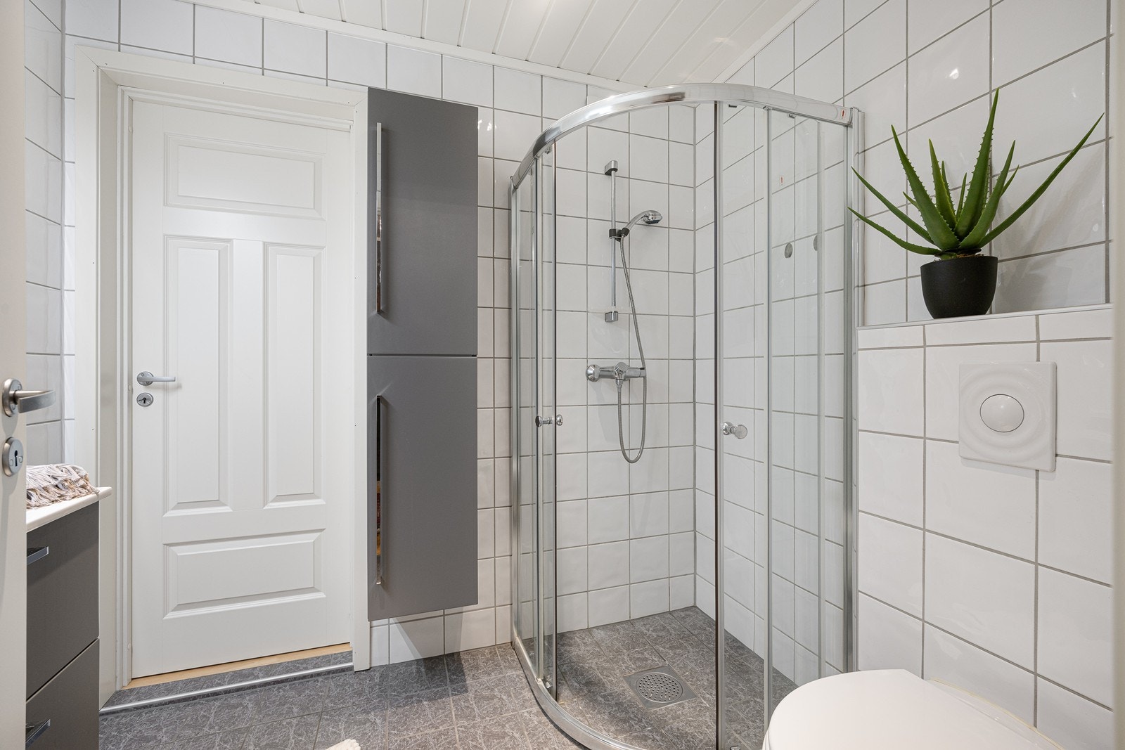 Videre har badet et vegghengt toalett og et dusjhjørne med skyvdører i glass. Galleribilde
