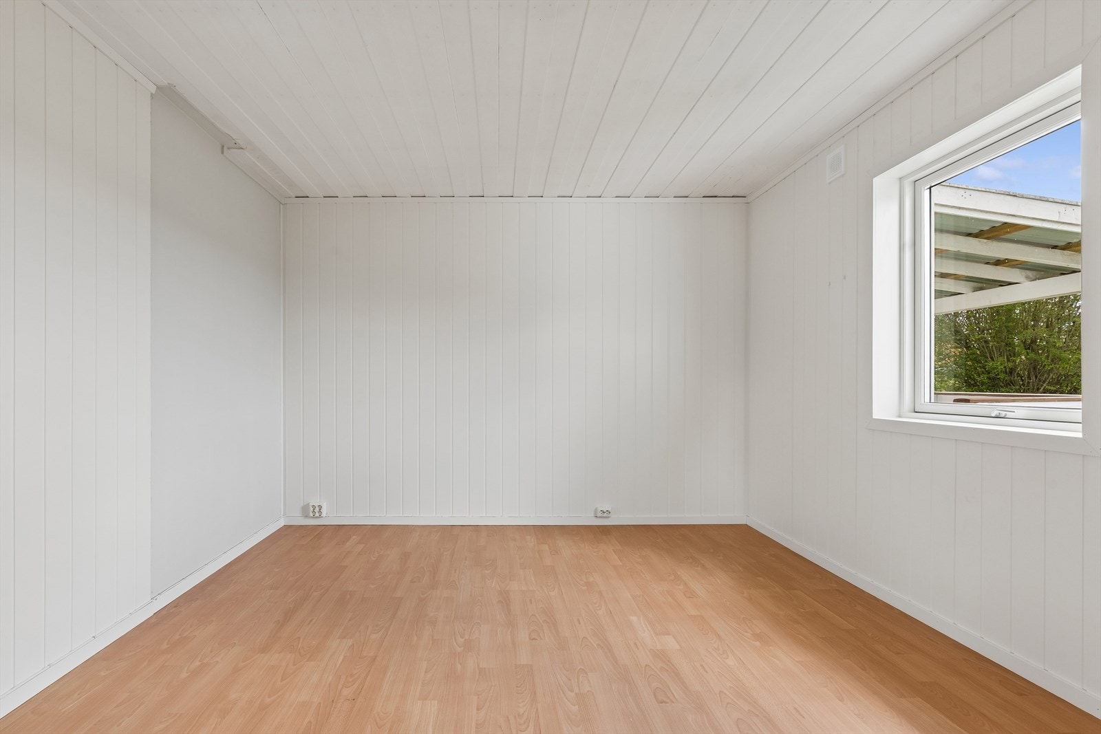 Boligens andre soverom, også dette med laminatgulv og lyse panelvegger. Galleribilde
