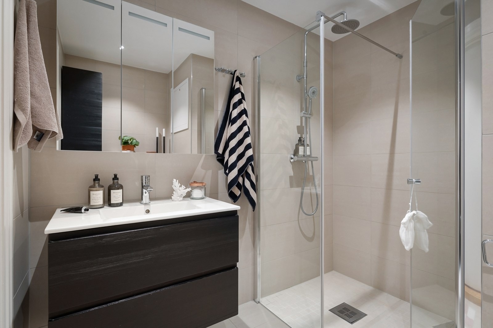 Det ene badet er utstyrt med fliser, gulvvarme, dusj på gulv og servant med skap. Galleribilde