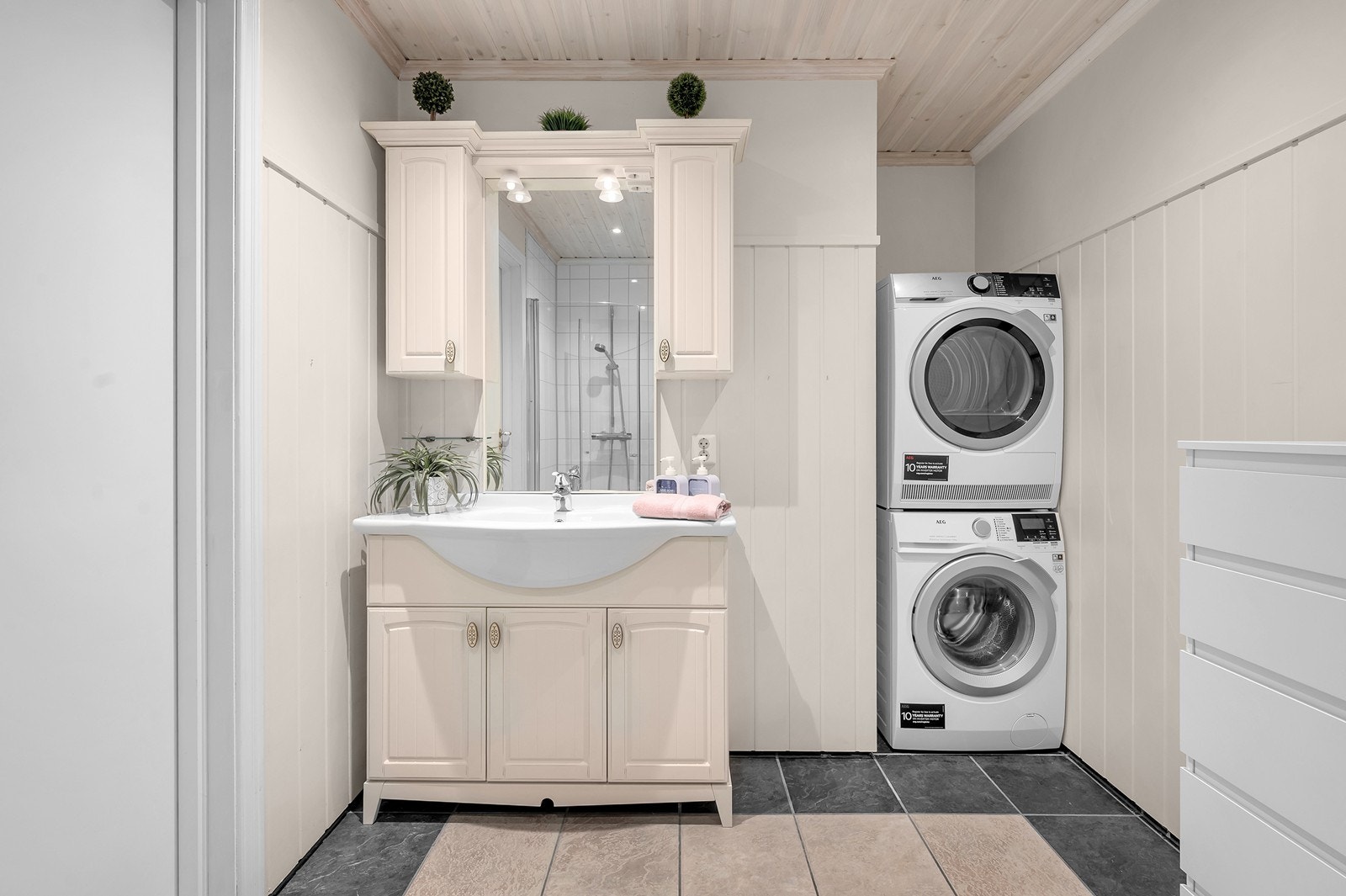 Badet har fliser på gulv og vegger i dusjområdet, med panelplater på øvrige vegger. Galleribilde