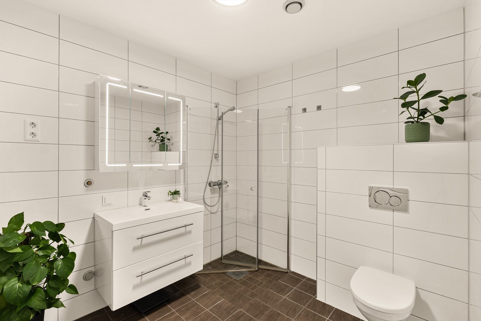 Flott helfliset bad med varme i gulv. Badet er utstyrt med servant med møblement/speil, belysning, vegghengt toalett, dusjgarnityr og dusjhjørne. Galleribilde