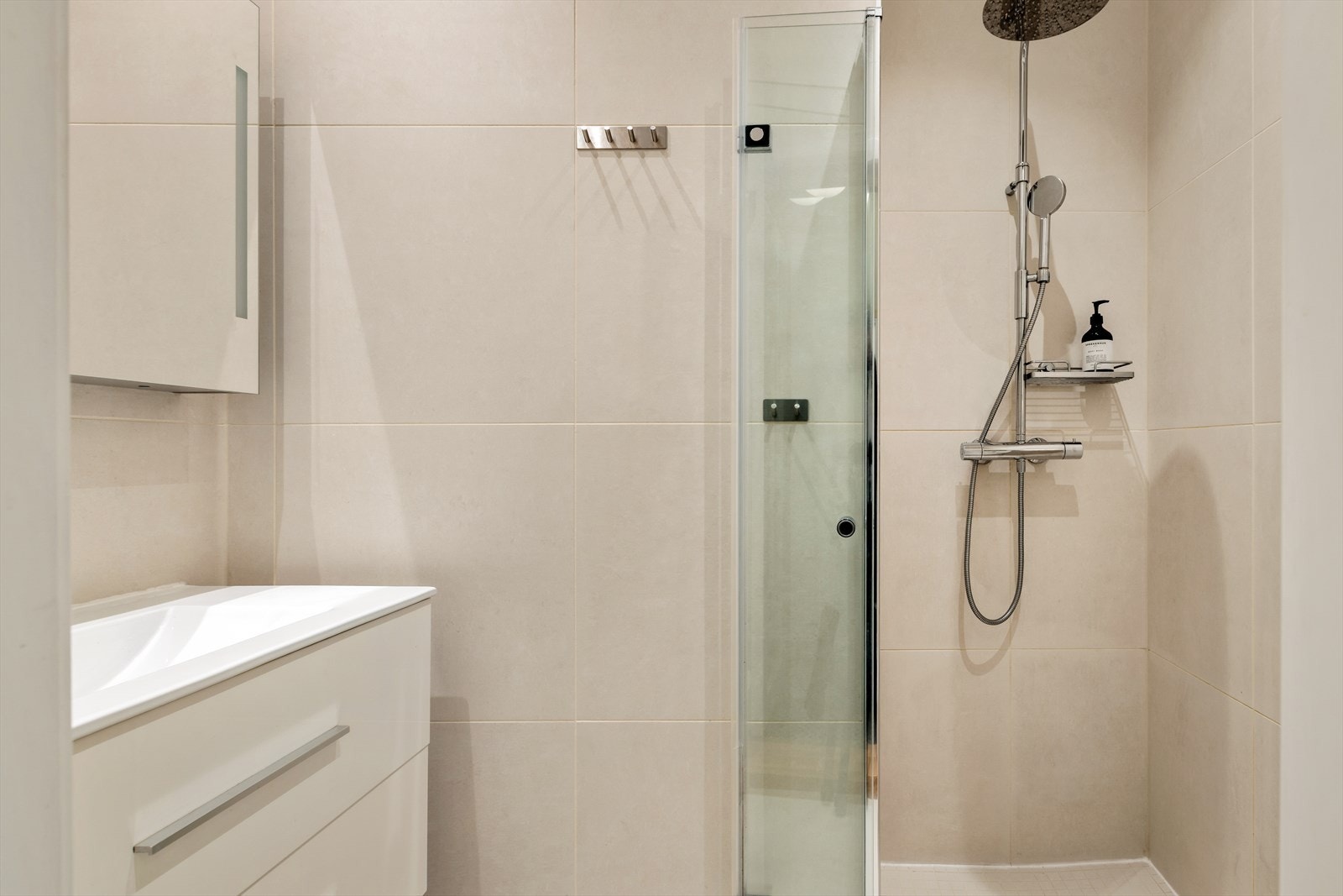 Badet er innredet med dusj med herdet glass, stilren baderomsinnredning og oppbevaringsmuligheter. Galleribilde