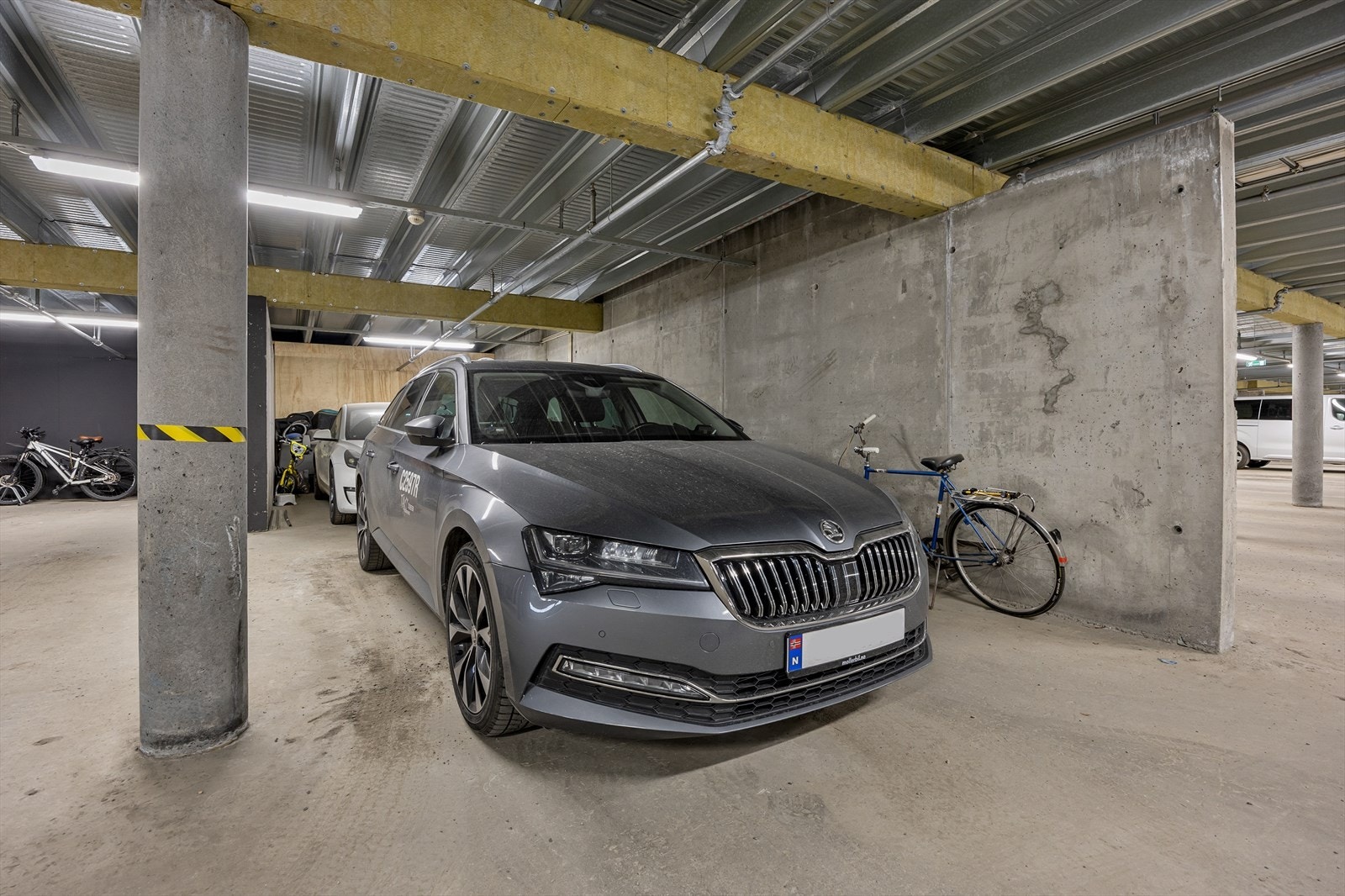 Til leiligheten hører en garasjeplass med plass til to biler i rekke felles anlegg, samt en ekstern sportsbod på 6,8 m². Det er montert en elbillader. Galleribilde