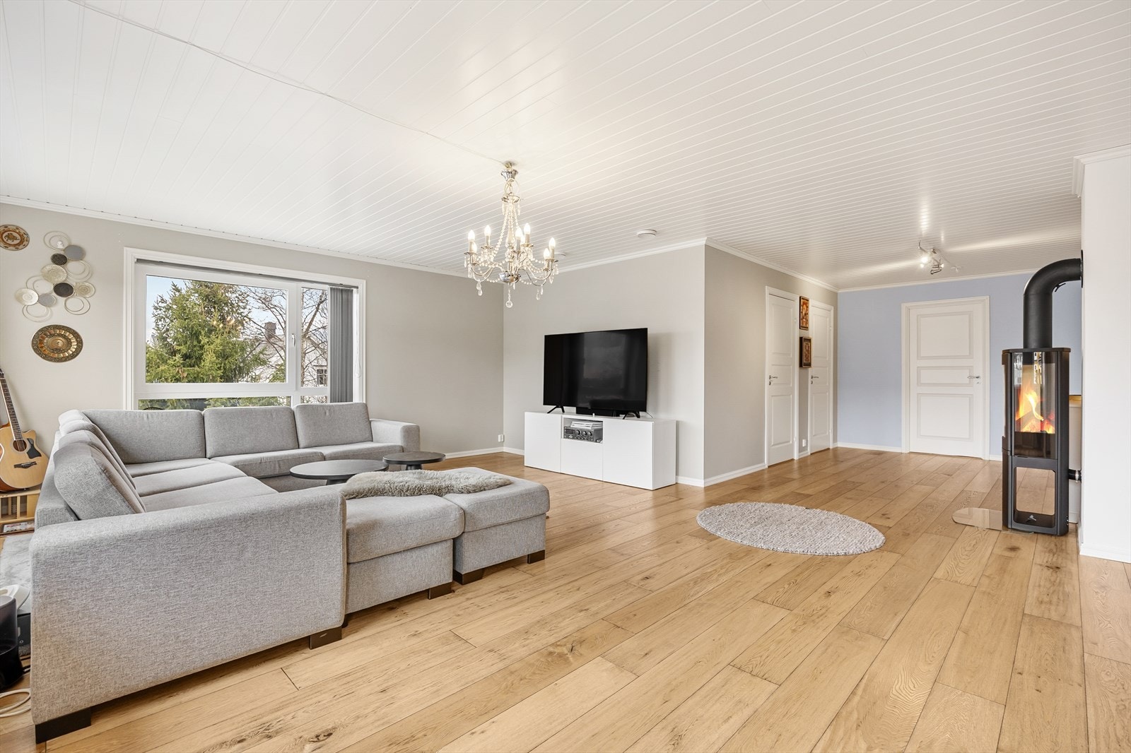Videre til den romslige stuen, med store vindusflater som gir godt med naturlig lys inn i boligen. Ildstedet gir god og lun varme i boligen. Galleribilde