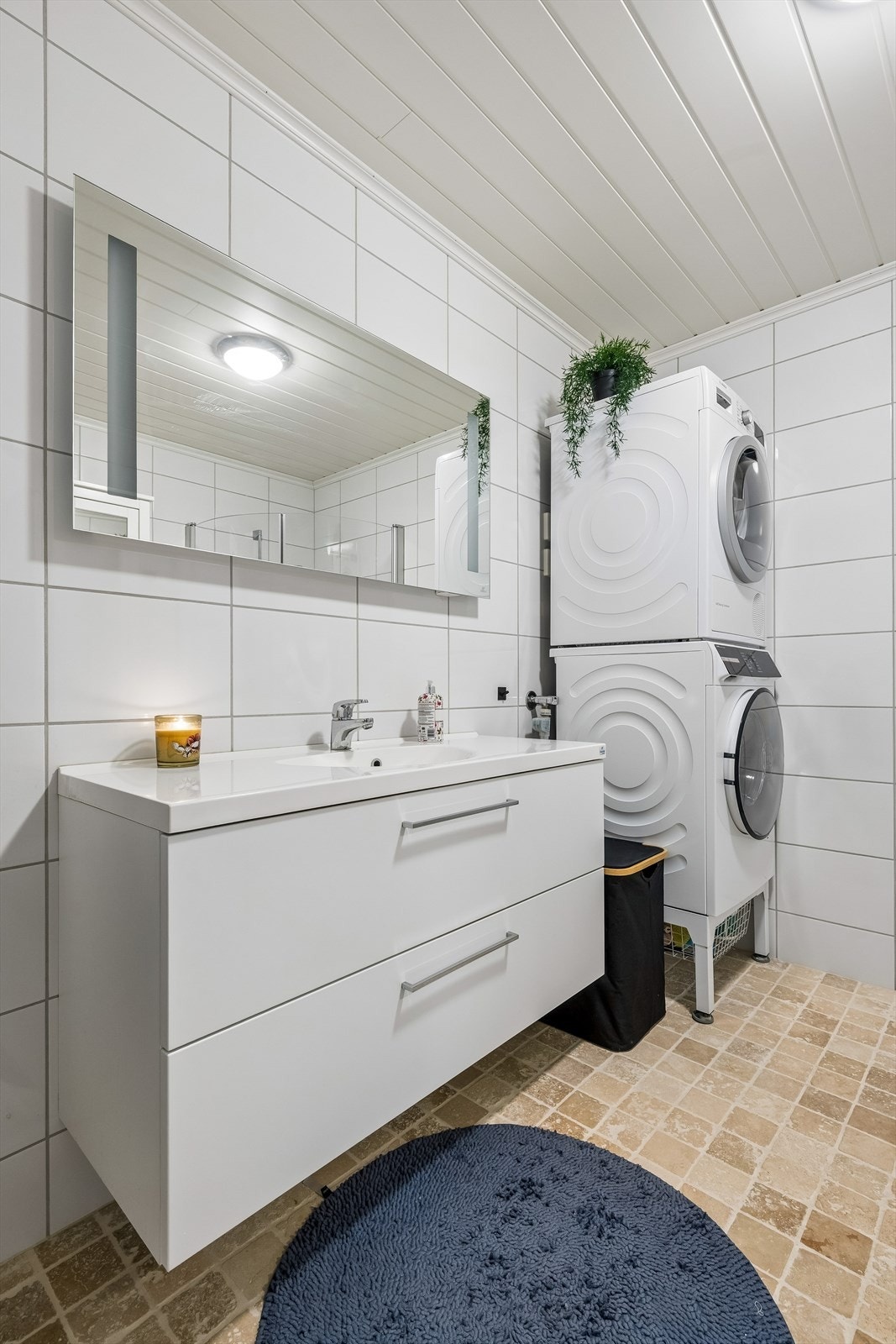 Baderomsinnredning med heldekkende servant og speil med integrert belysning. Det er opplegg for vaskemaskin. Galleribilde