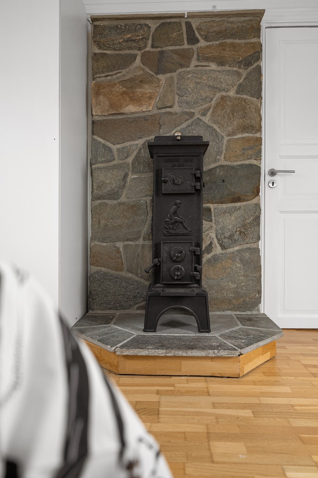 Detalj av ildstedet, plassert foran en vegg med naturstein. Galleribilde