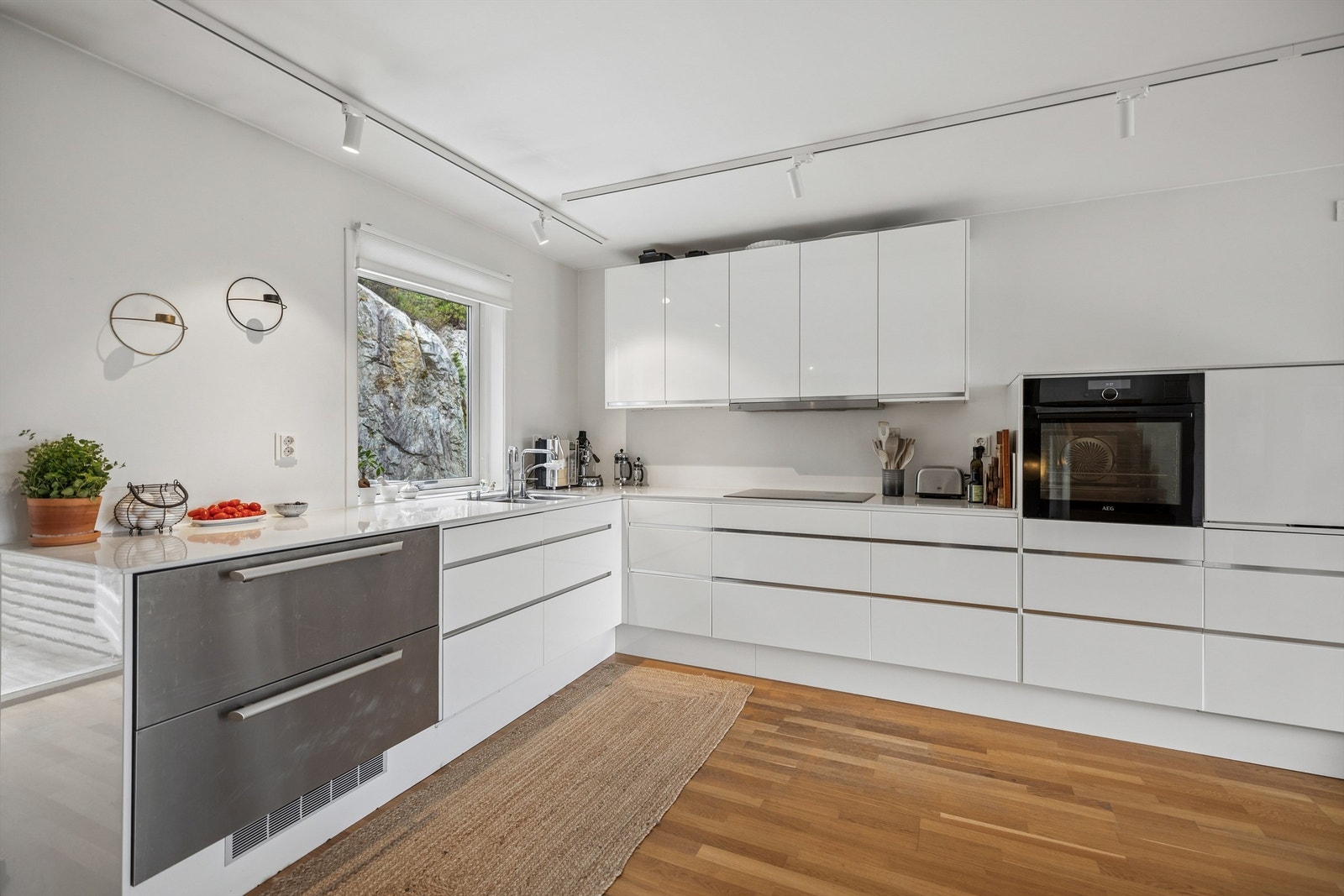 Kjøkkeninnredning fra 2015. Innredningen har slette fronter og benkeplate i kompositt, kombinert med underlimt oppvaskkum i metall og ett-greps armatur. Galleribilde