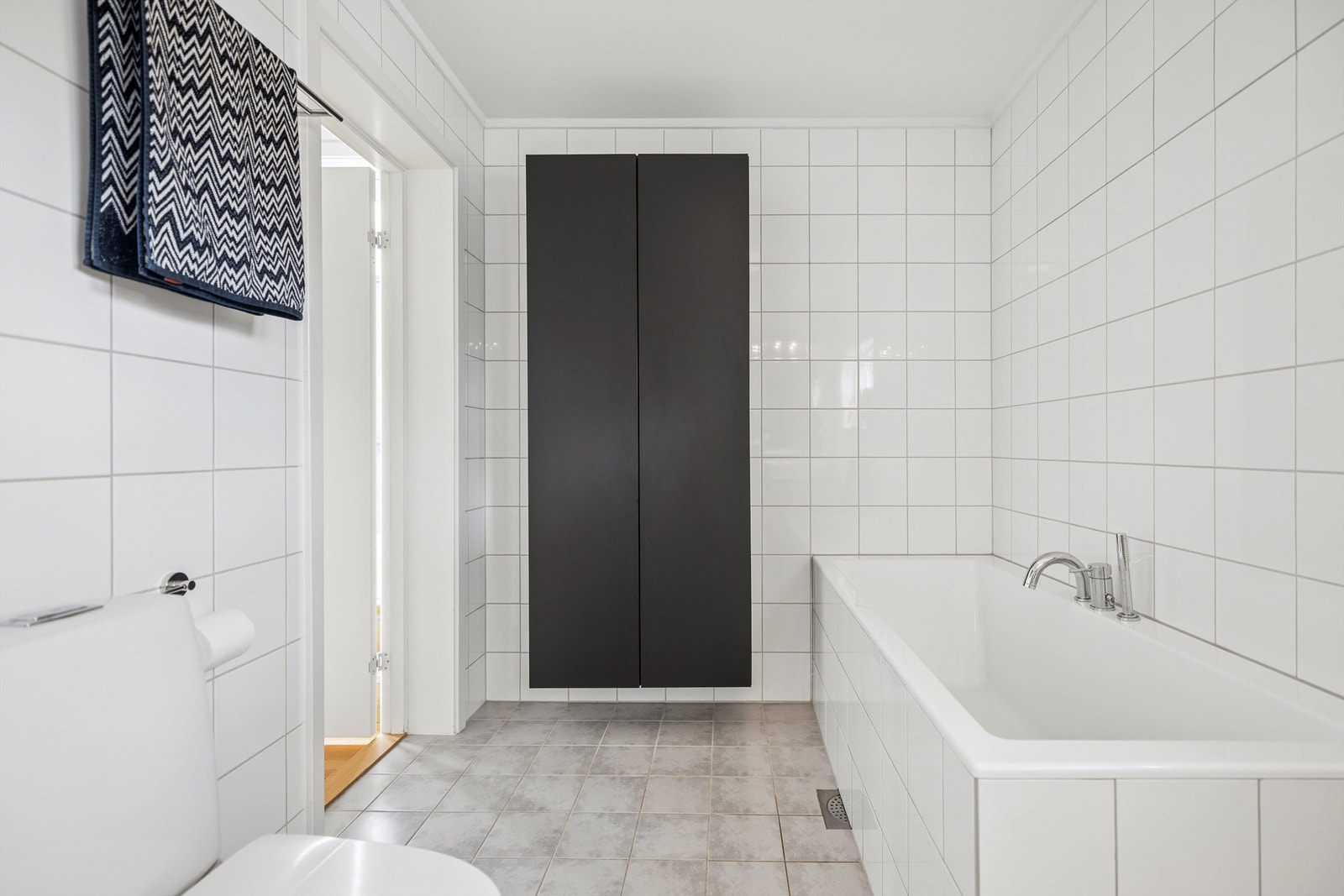 Badet er utstyrt med flislagt badekar og praktisk vegghengt baderomsinnredning som gir gode oppbevaringsmuligheter. Galleribilde