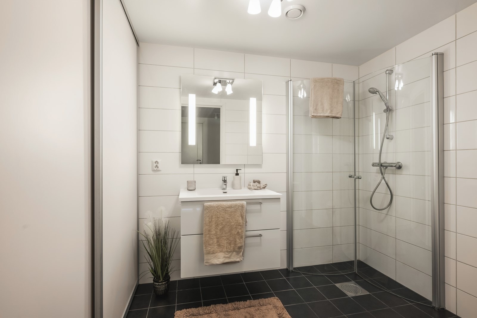 Lyst og pent baderom med flislagt gulv med varme i og lyse veggplater. Galleribilde