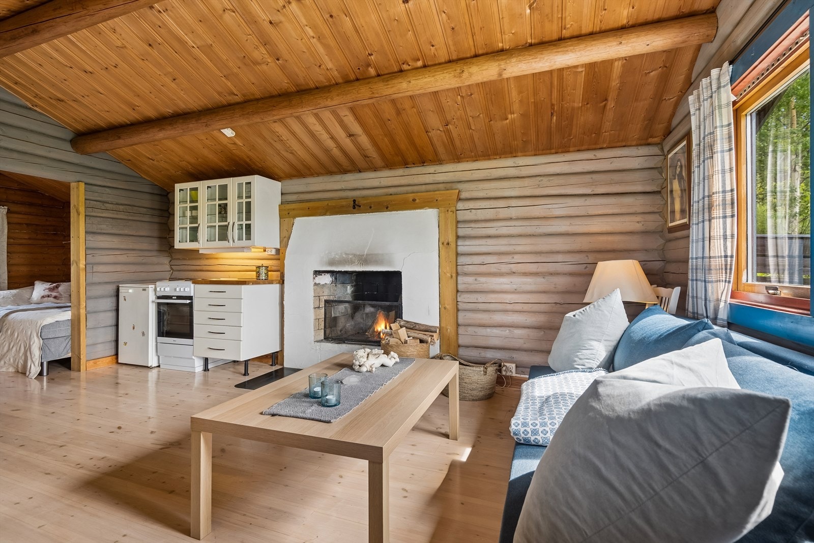 Hovedrommet har en åpen løsning med tømmervegger, laminat på gulv og panel i himling med synlige tømmeråser. Galleribilde