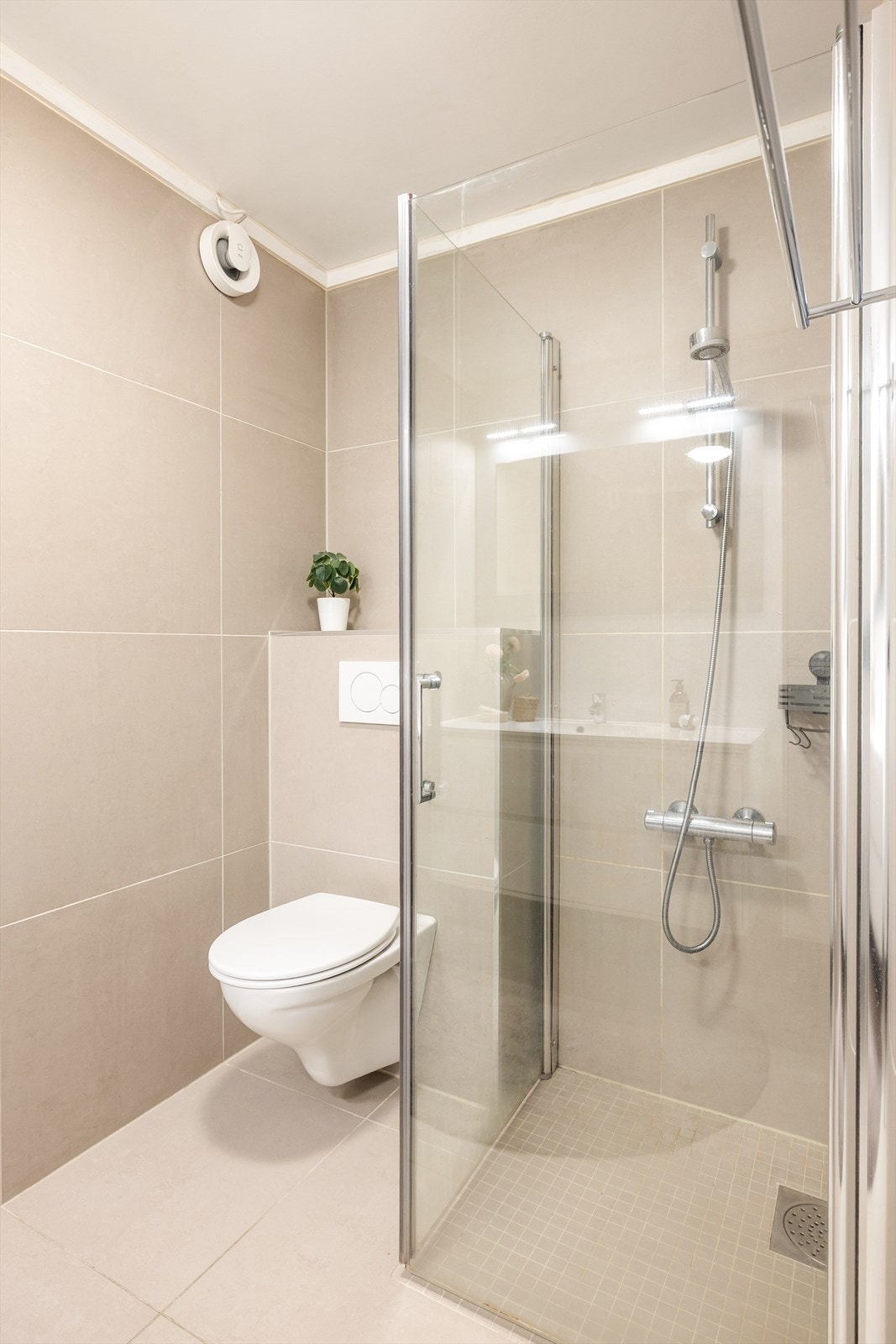 - Badet er innredet med vegghengt toalett, benkeskap med servant, opplegg for vaskemaskin og dusjdører i glass - Galleribilde