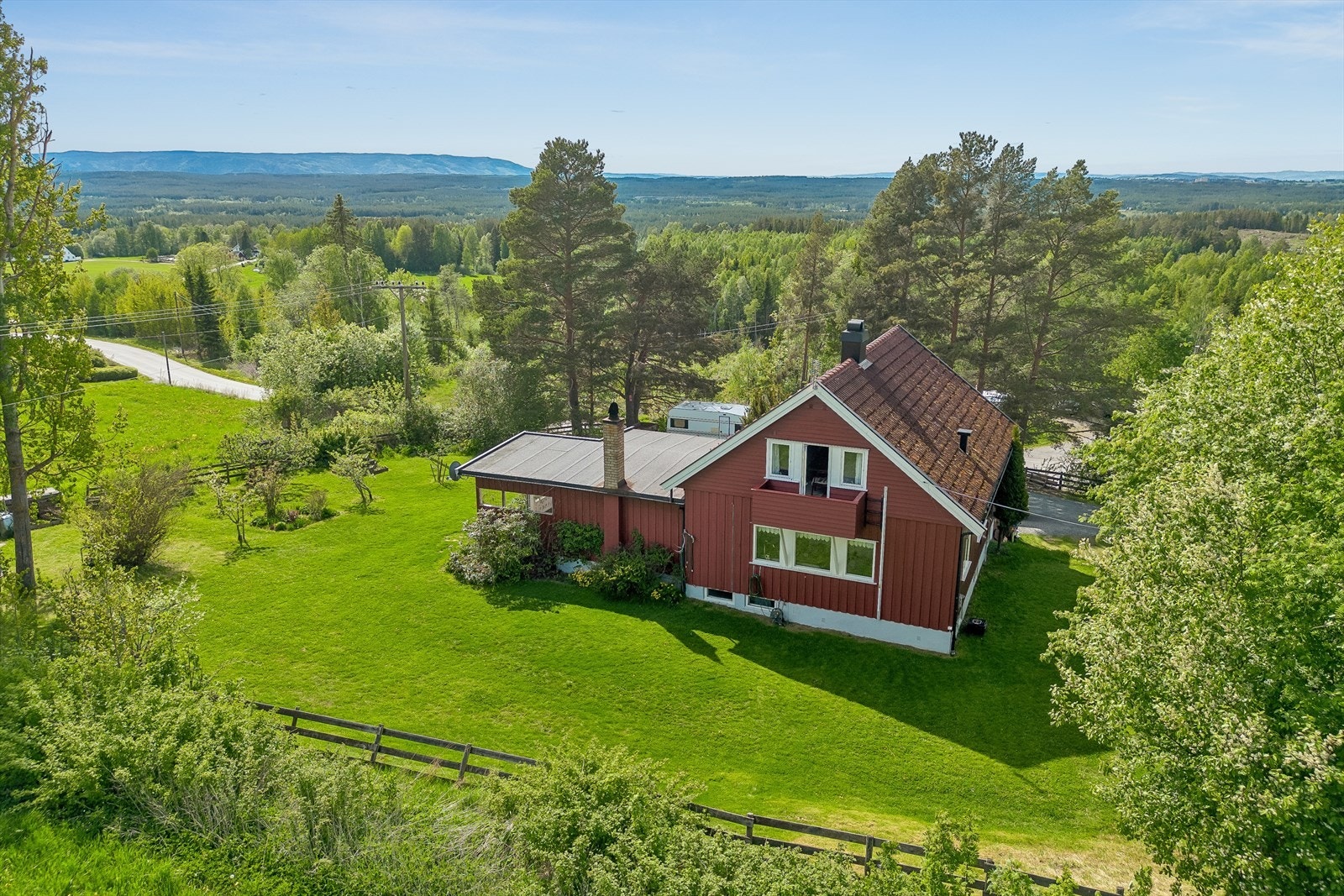 Eiendommen ligger på en romslig, skrånende tomt med hageanlegg, plen og variert beplantning. Galleribilde