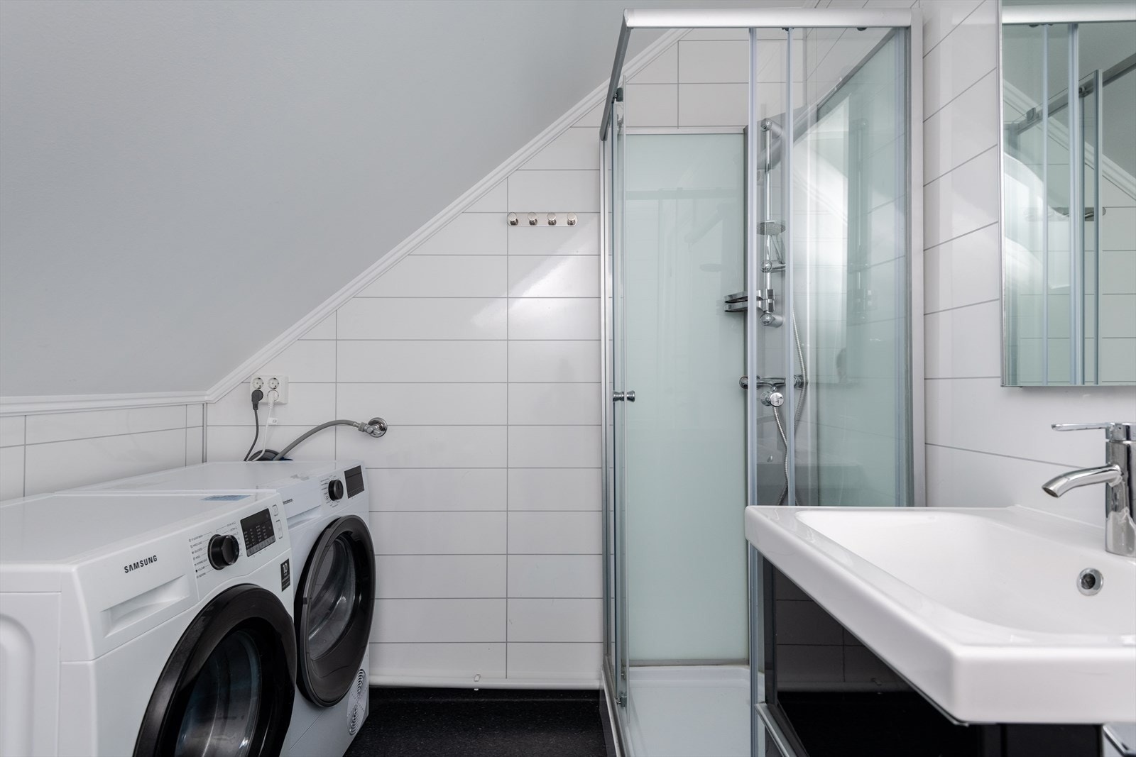 Plass til vaskemaskin og opplegg for tørketrommel gir praktiske løsninger på badet. Galleribilde