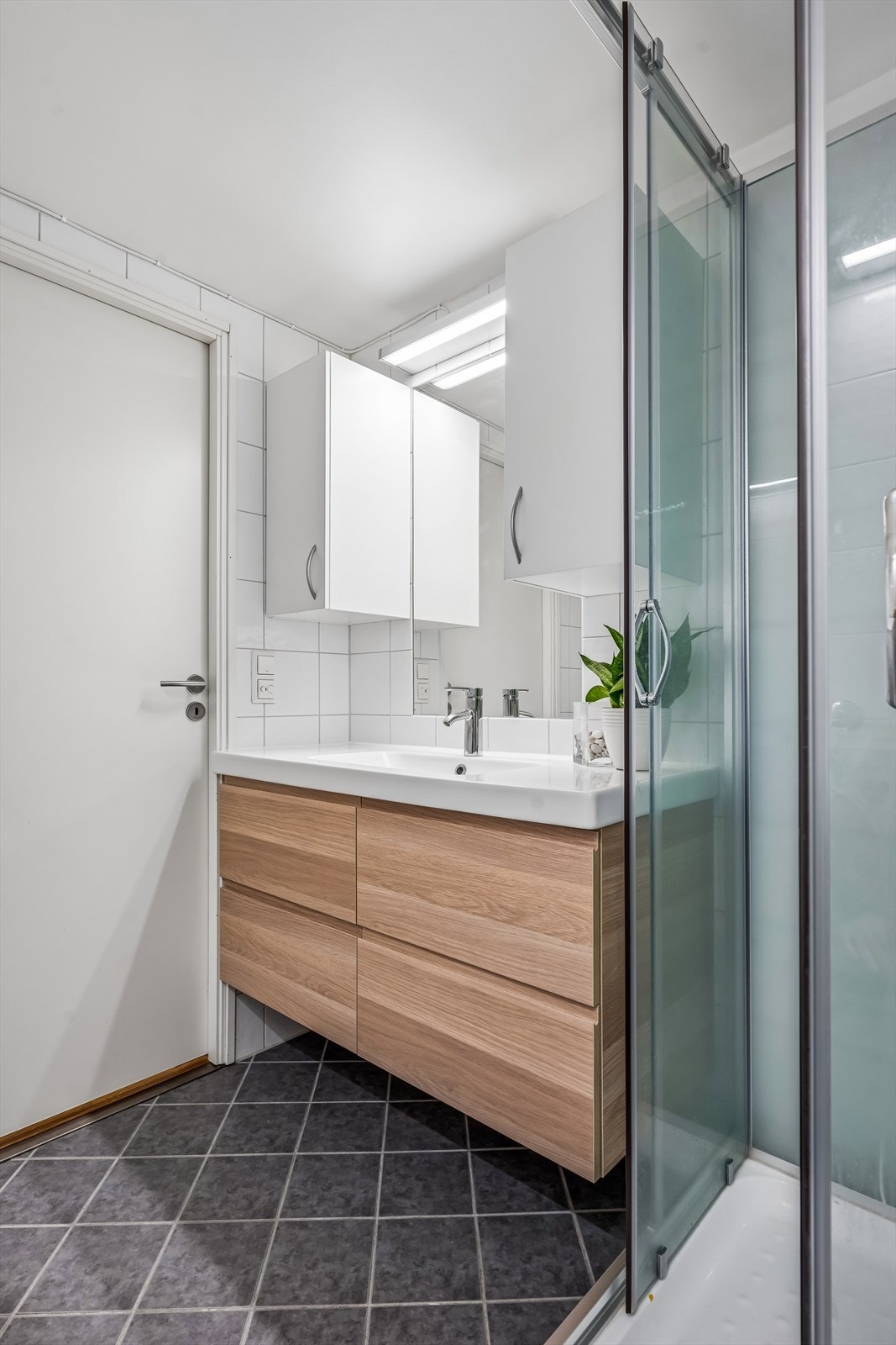 Badet er utstyrt med dusjkabinett (montert i 2017), vegghengt wc og servantinnredning med skuffer og overskap. Galleribilde