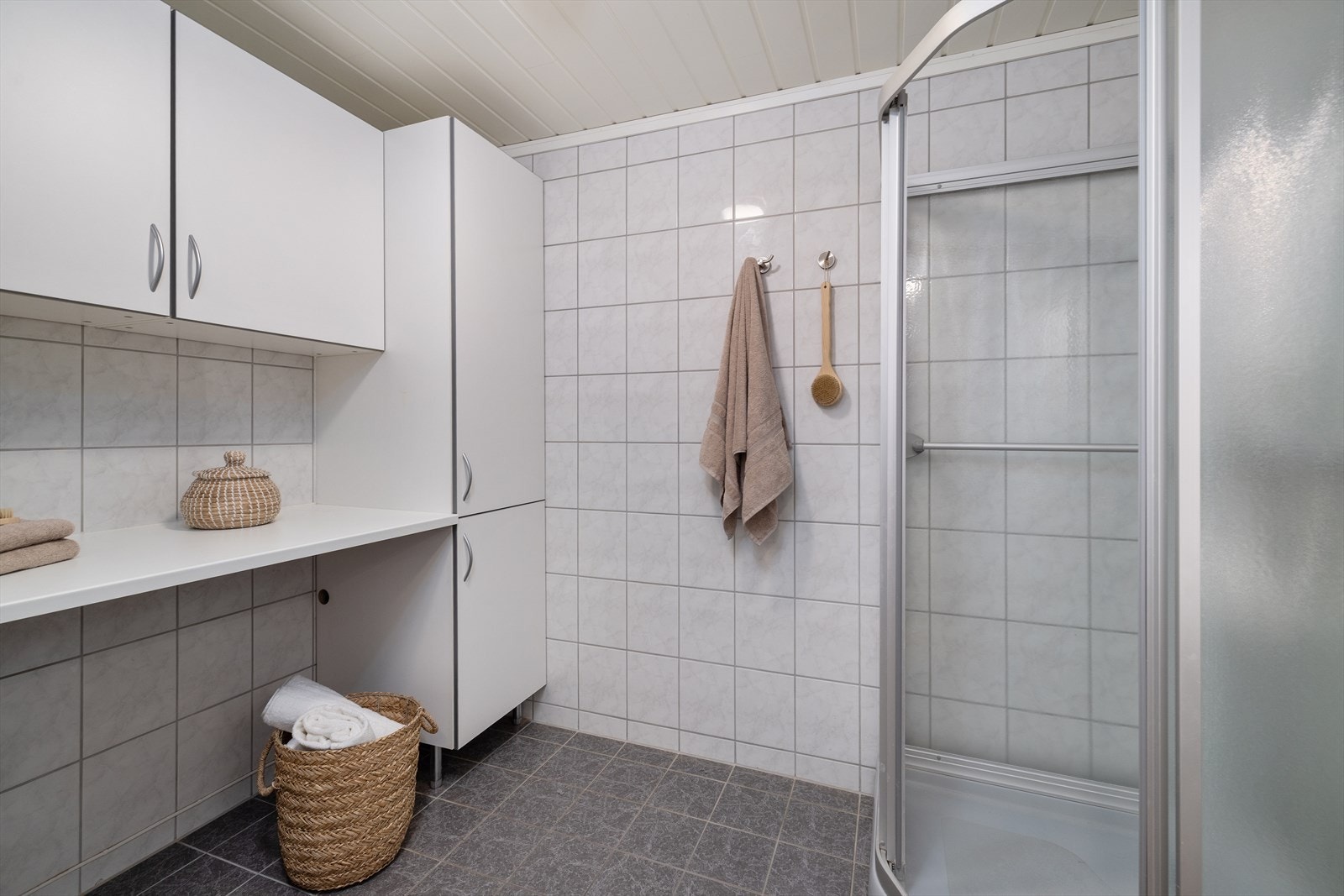Praktisk vaskeromsdel med benkeplate, skap og opplegg for vaskemaskin. Galleribilde