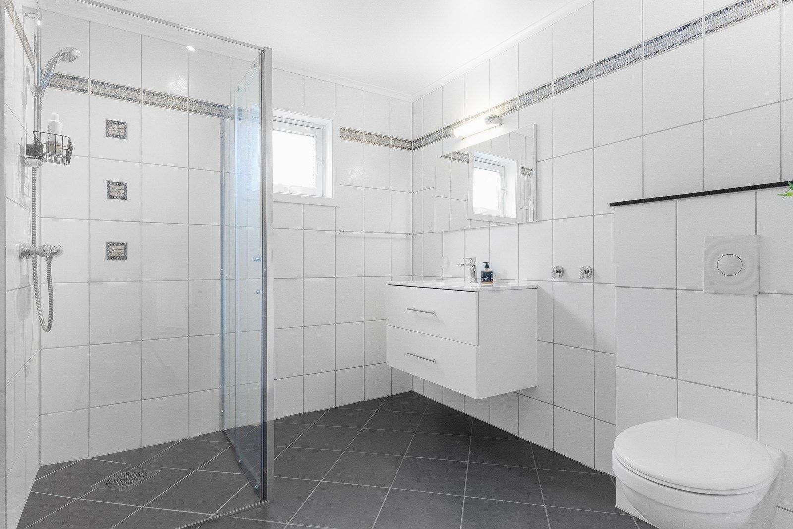 Delikat, helfliset bad med dusjhjørne i glass, moderne servantinnredning og gulvvarme. Galleribilde