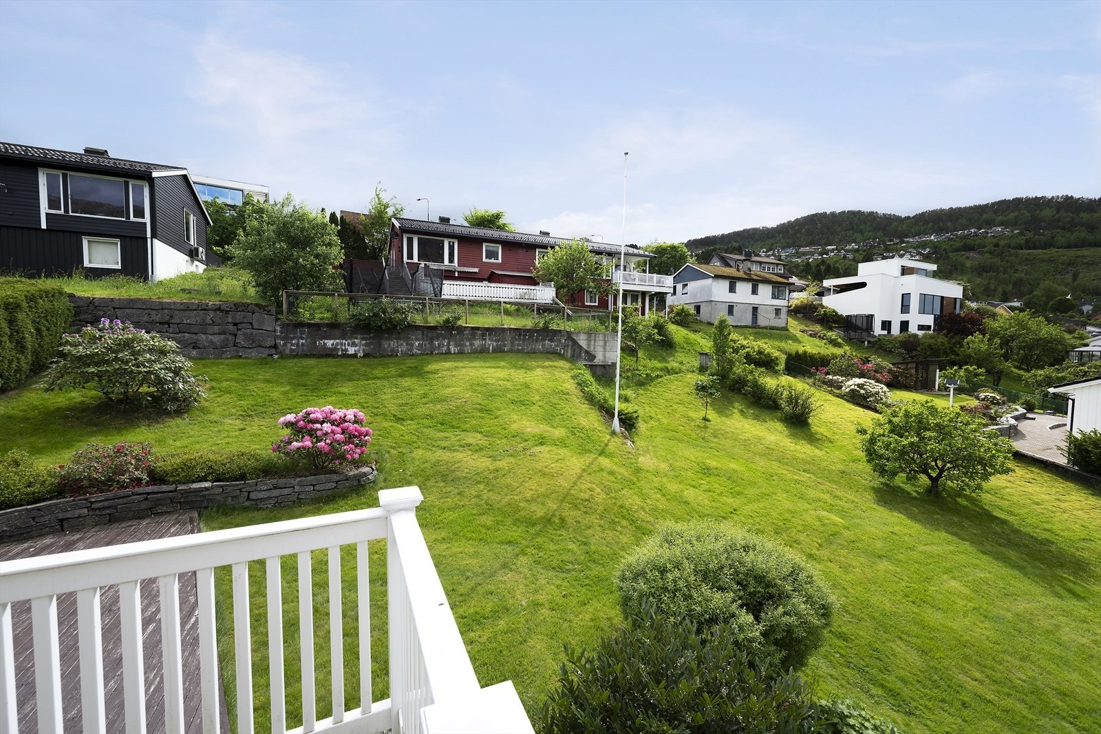 Tomten er pent opparbeidet med plenareal, murer og variert beplantning. Galleribilde