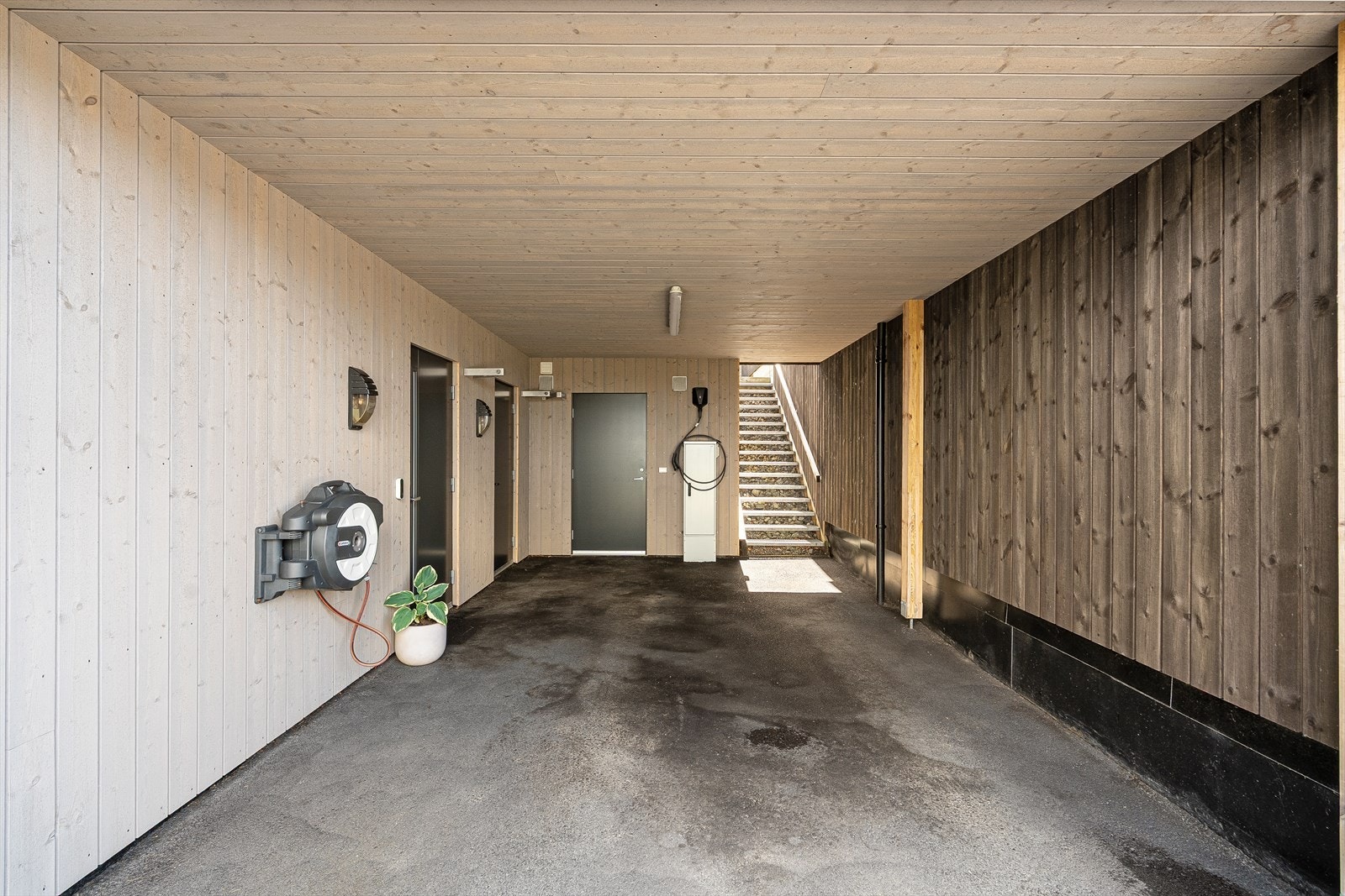 Inngang til boligen gjennom carport. Her har man både hovedinngang og en bi-inngang, samt trapp opp til hage og uteområdet. Galleribilde