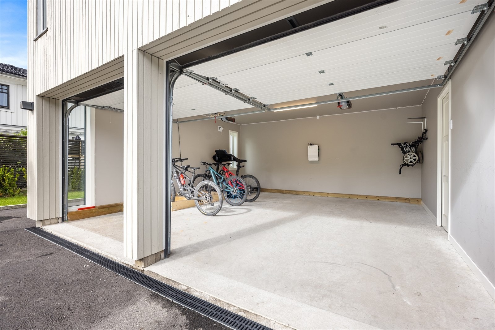 Boligen har stor integrert dobbelgarasje med elektriske porter og elbillader. Her er det muligheter for å gå videre inn til boligen etter parkering. Galleribilde