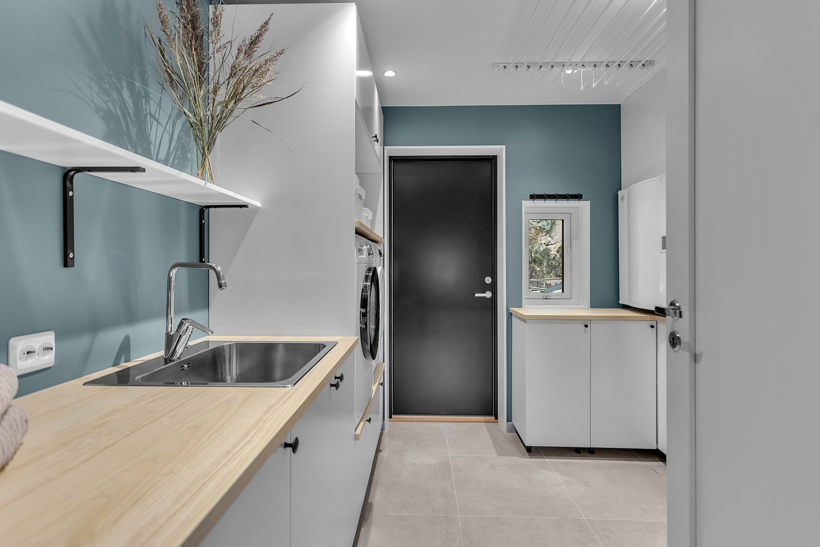 Praktisk og funksjonelt separat vaskerom (godkjent som bod) med egen inngang, ideelt også som grovgang. Rommet er innredet med rikelig skap- og benkeplass, samt en vask og opplegg for både vaskemaskin og tørketrommel plassert i behagelig arbeidshøyde. Galleribilde