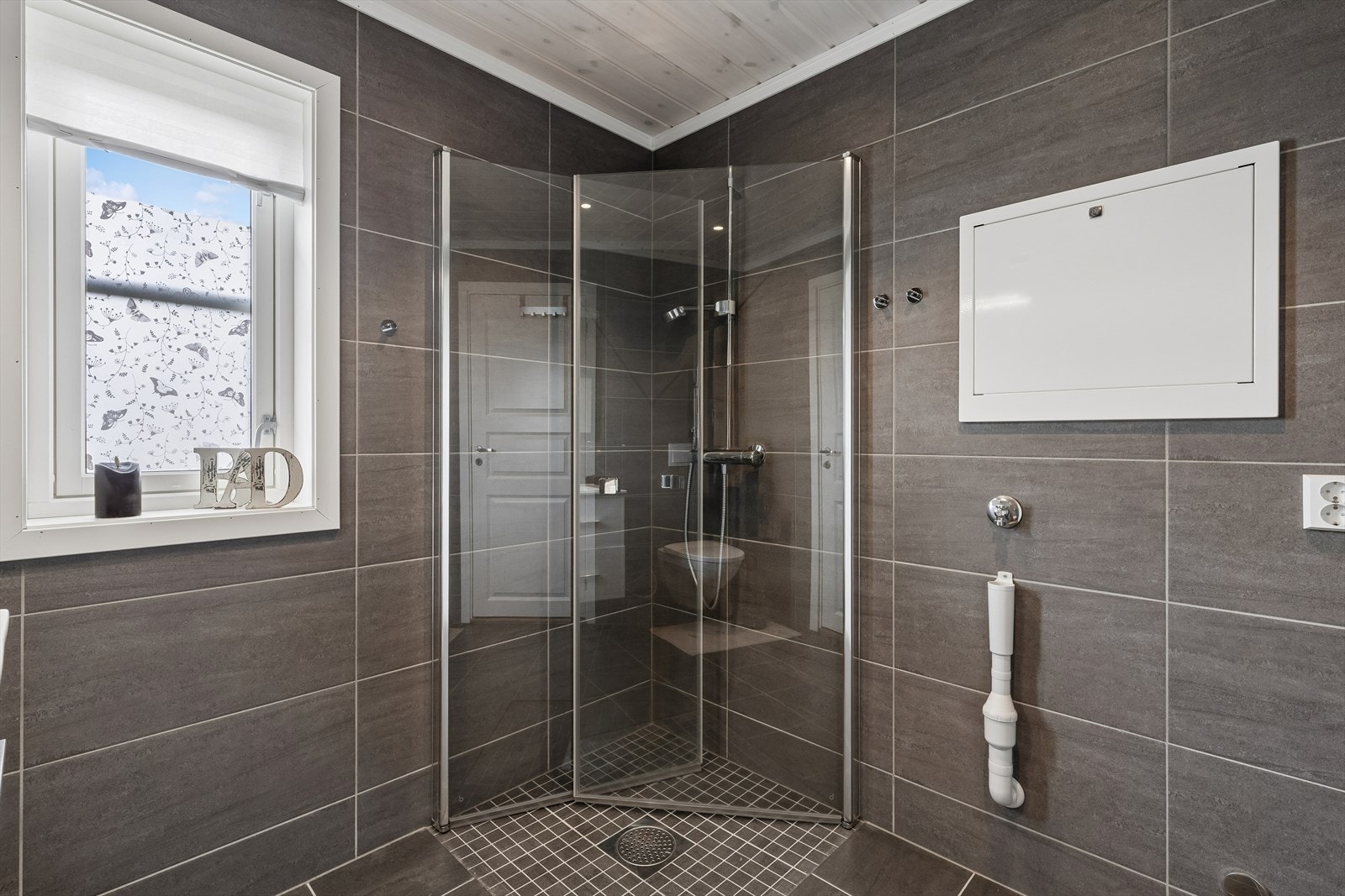Hytta har to bad. Dette badet er utstyrt med dusjhjørne med innfellbare glassdører. Det er opplegg for vaskemaskin på dette rommet. Galleribilde