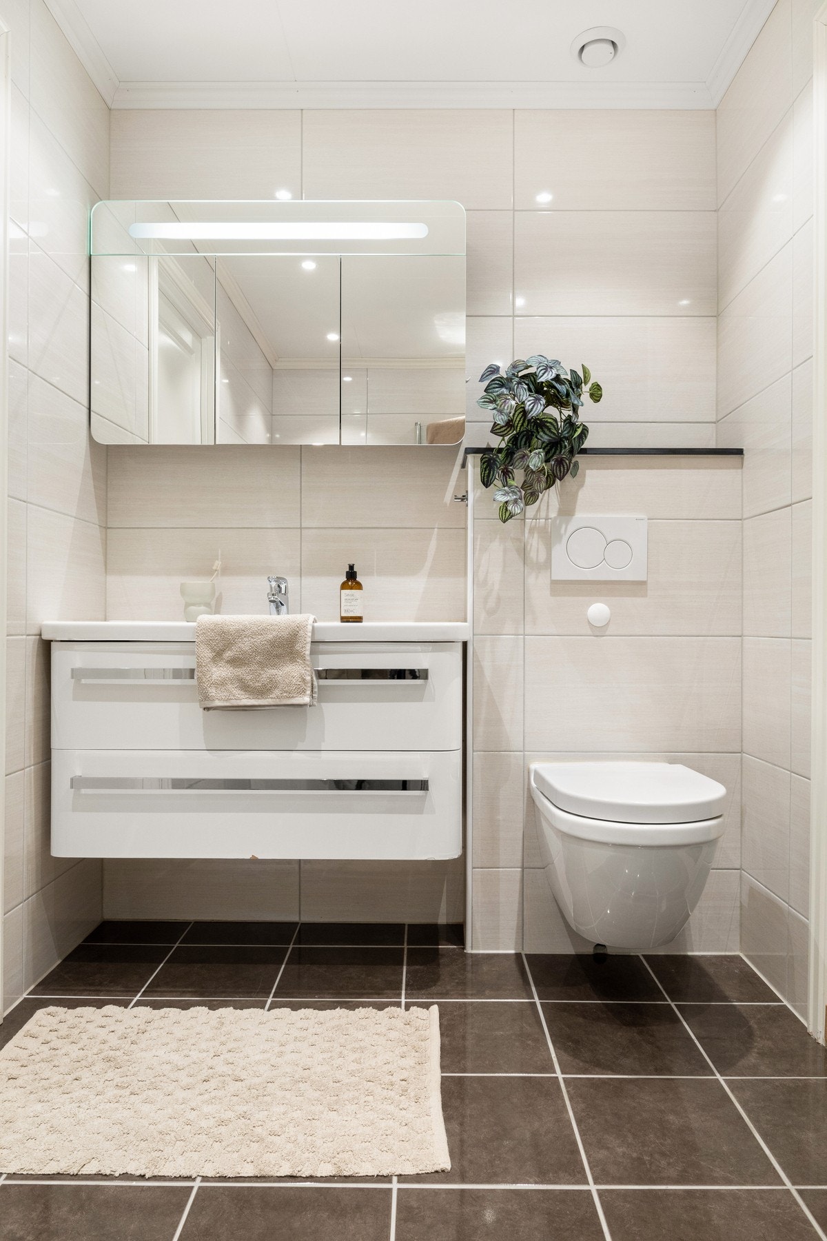 Badet er pent og funksjonelt innredet med vegghengt toalett, helstøpt servant og servantskap med slette fronter. Galleribilde