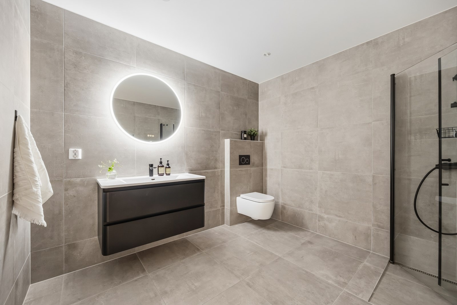 Badet i leiligheten holder tilsvarende god standard som resten av boligen, med flislagte overflater på gulv og vegger, varmekabler og malt himling med spotlights. Galleribilde