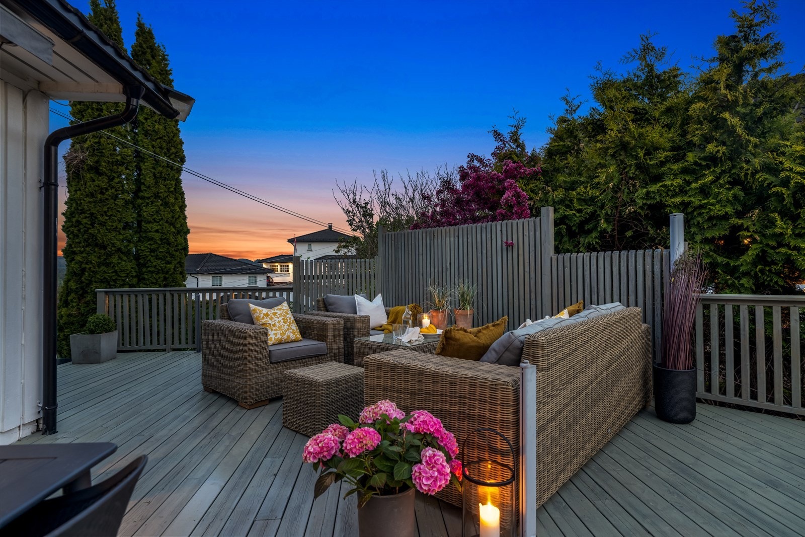 Stor og romslig terrasse som strekker seg rundt 3 sider av boligen. Bildet viser terrasse på oversiden av boligen som har kveldssol. Galleribilde