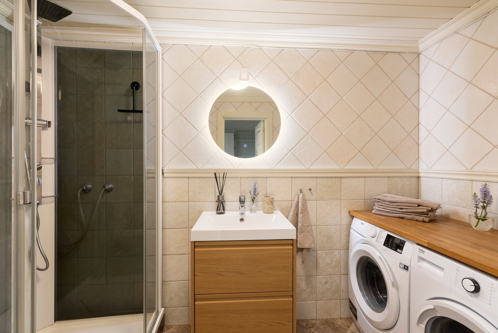 Badet er flislagt og utstyrt med dusjkabinett, toalett, nyere baderomsinnredning samt opplegg for vaskemaskin og tørketrommel. Galleribilde