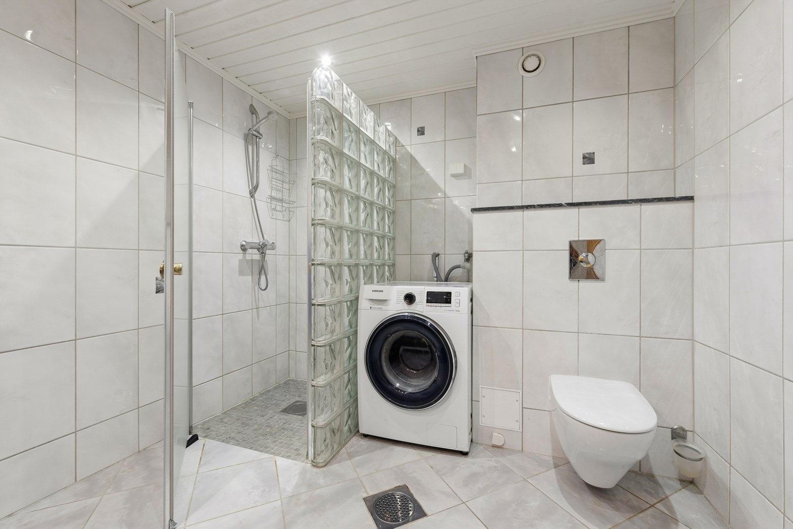 Badet har en innredning med profilerte fronter og inneholder servant, klosett, dusj og opplegg for vaskemaskin Galleribilde