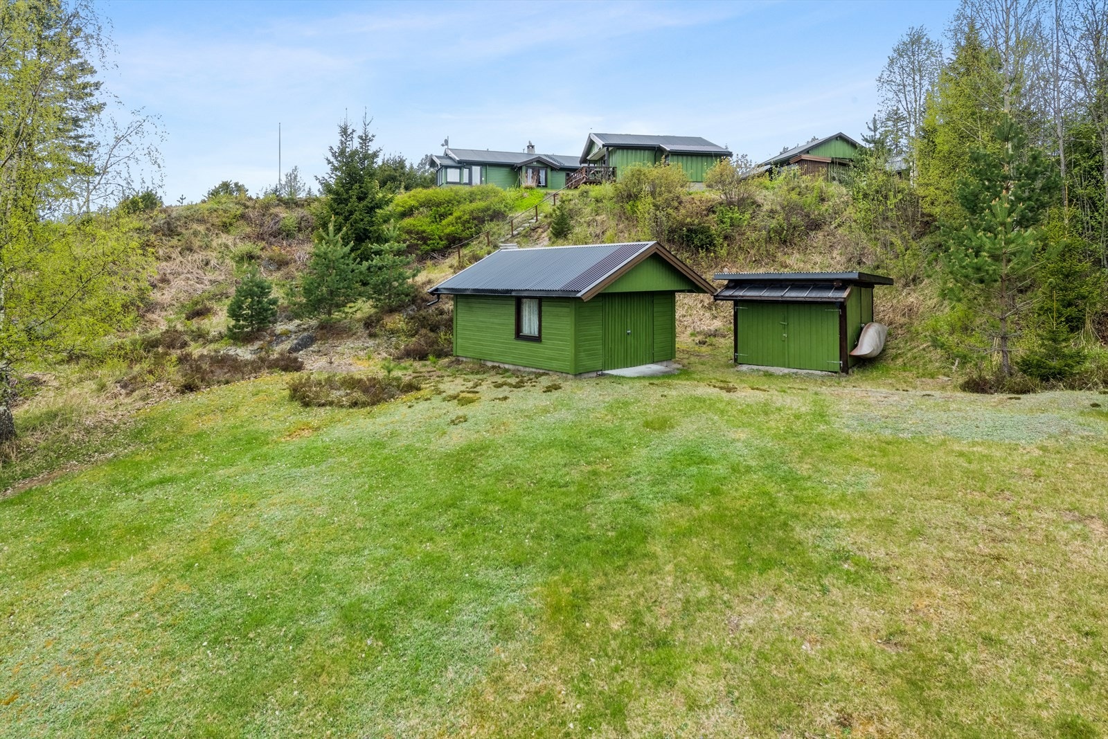 På nedre del av tomten har man en ekstra garasje og en båtgarasje/uthus Galleribilde
