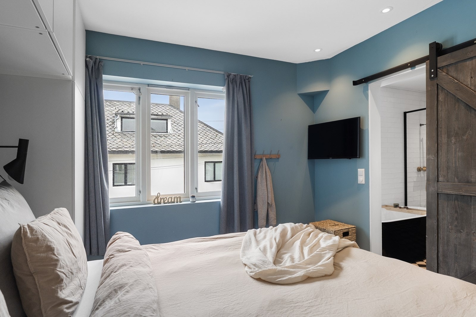 Rommet har direkte adgang til badet via en skyvedør i rustikt tre med sort skinne. Galleribilde