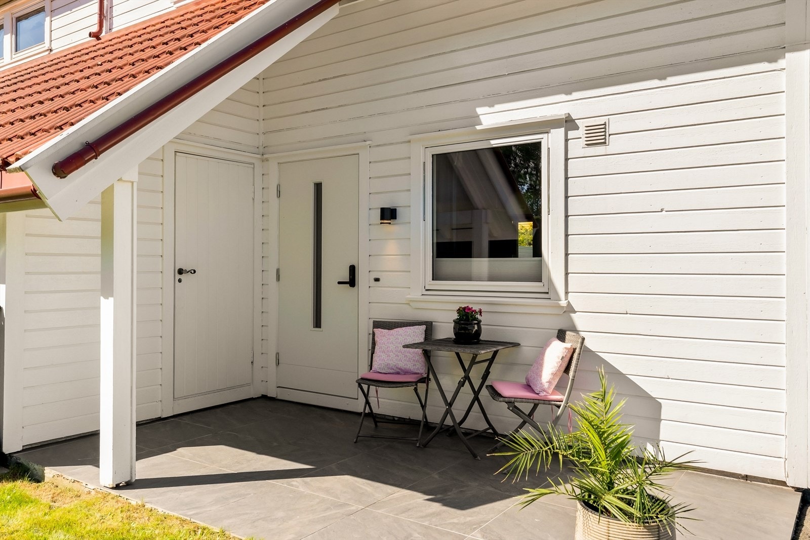 Overbygget inngangsparti med plass til en liten sittegruppe. Galleribilde