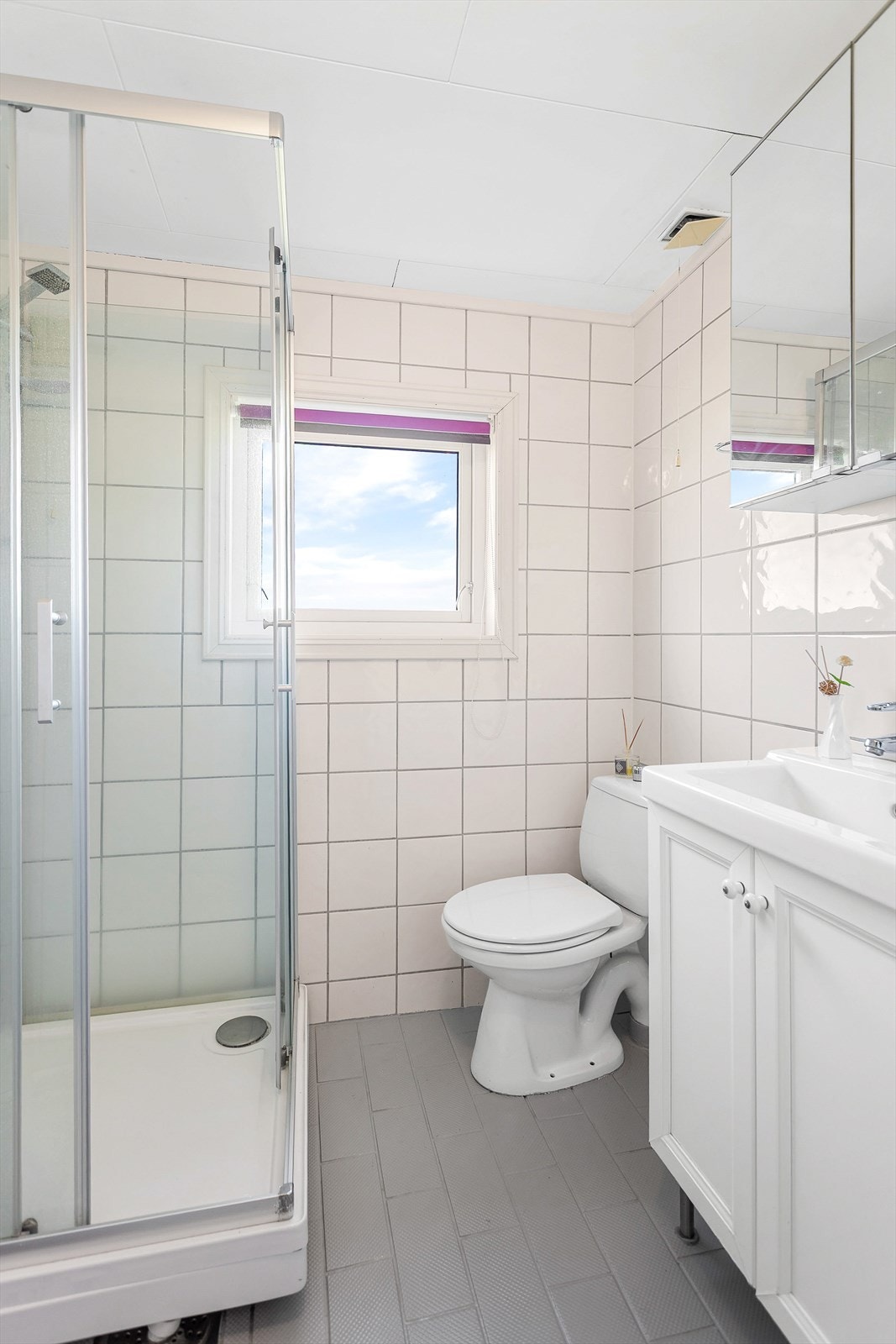Badet har flislagte vegger og gulv med elektriske varmekabler, samt dusjkabinett og servantinnredning. Galleribilde