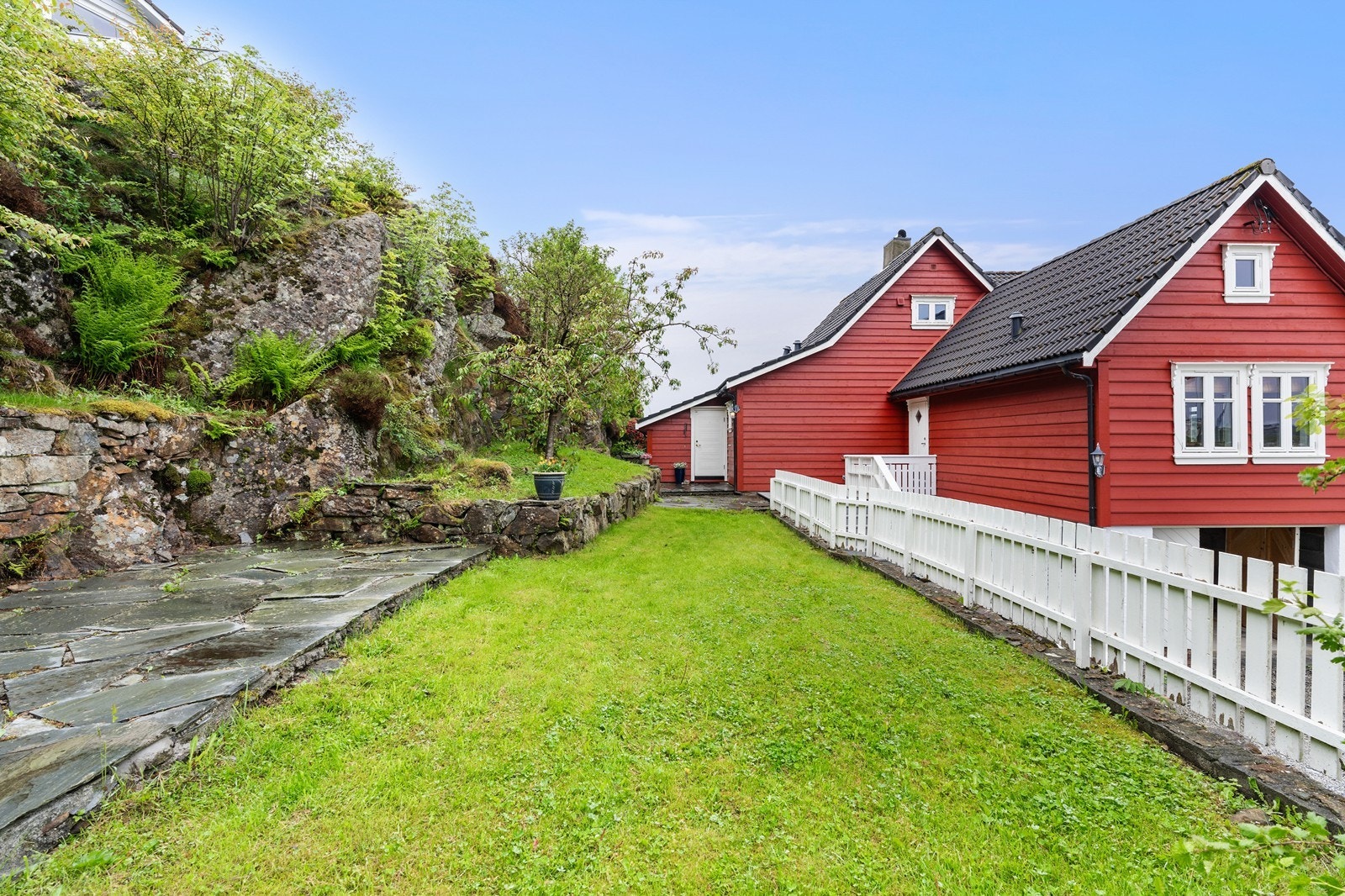 Uteområdet har flislagte partier, plenarealer og beplantning Galleribilde
