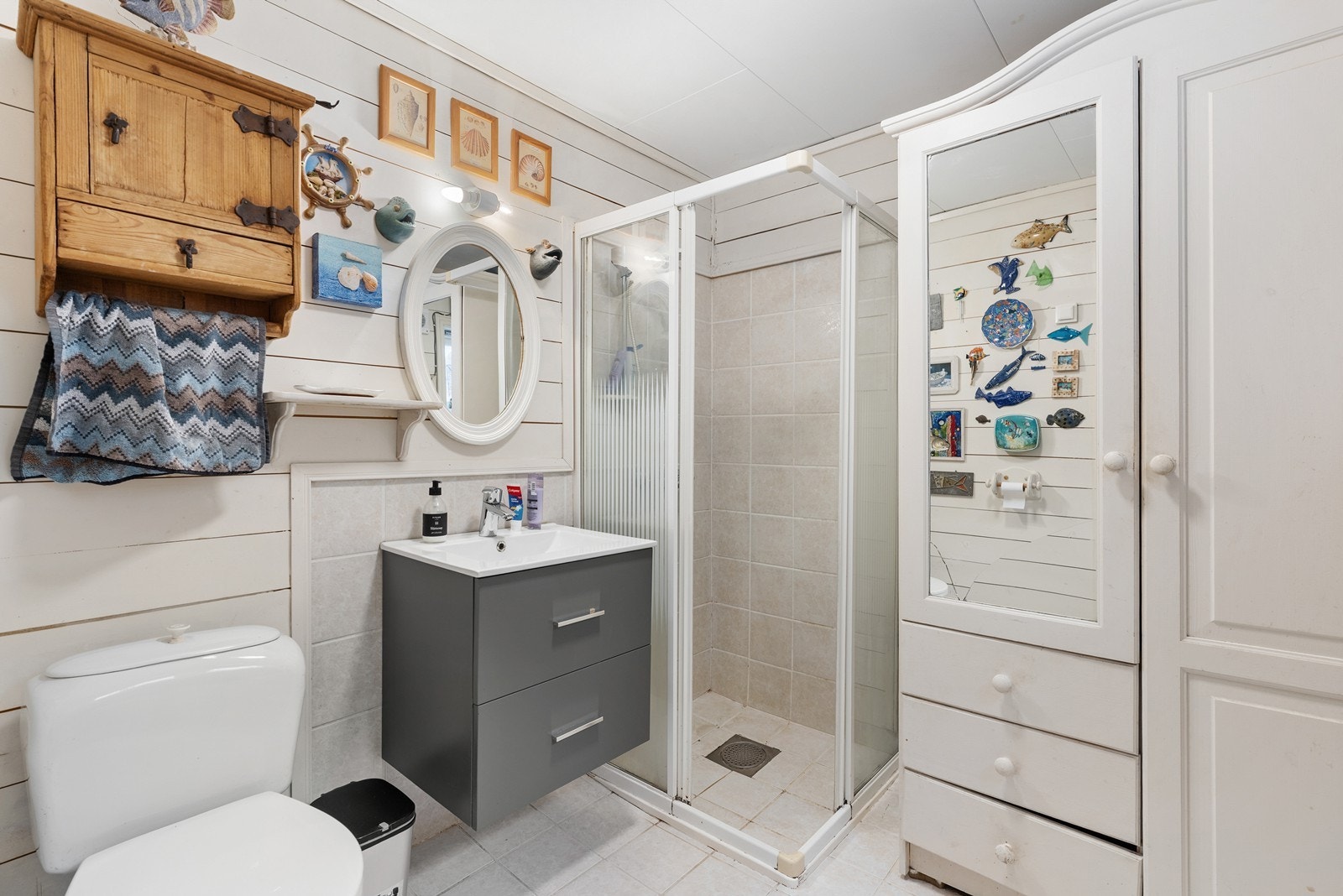 Badet med fliser på gulv med varmekabler, utstyrt med servant, toalett og
dusjvegger/hjørne. Galleribilde