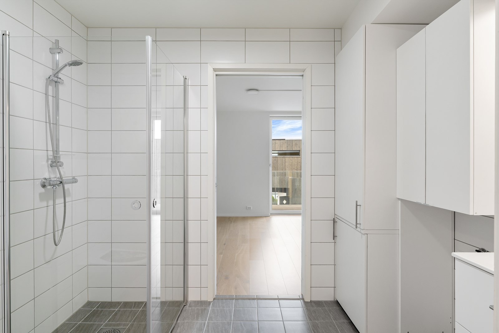 Badet har et praktisk dusjhjørne med innfellbare dører og opplegg for vaskemaskin. Galleribilde