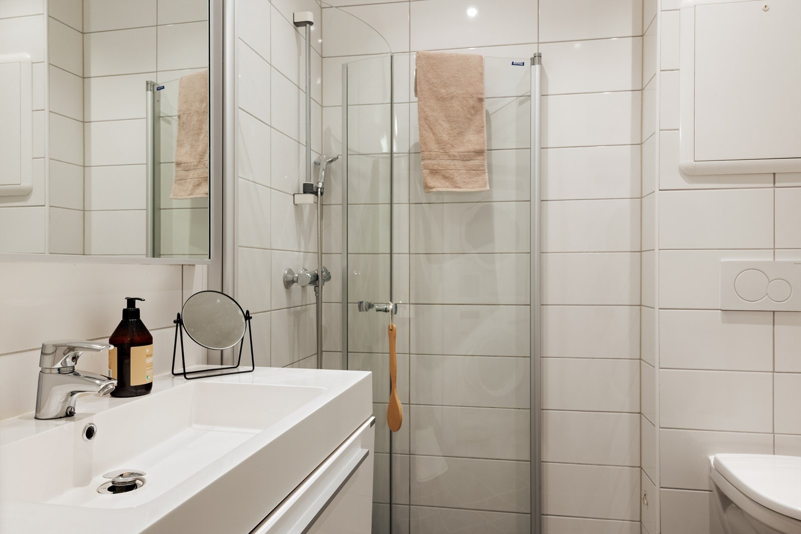 Badet er helfliset og fremstår moderne og funksjonelt. Badet er utstyrt med nedfelt servant, veggmontert toalett, dusjvegger/hjørne, varmtvannstank og opplegg for vaskemaskin. Galleribilde