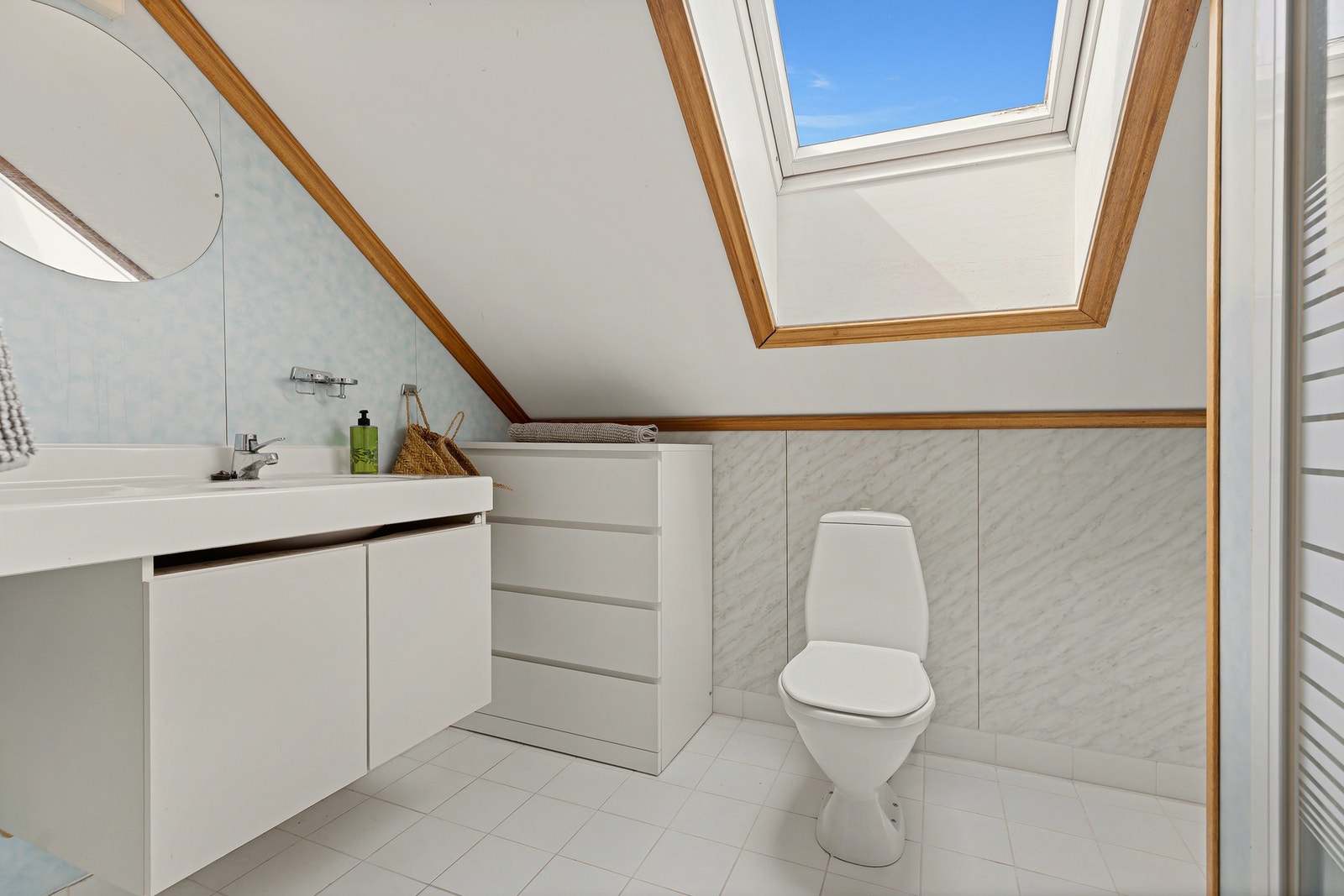 Badet i loftsetasjen fremstår lyst, og funksjonelt, med en gjennomført innredning og en lun atmosfære. Det store takvinduet slipper inn rikelig med naturlig dagslys. Galleribilde