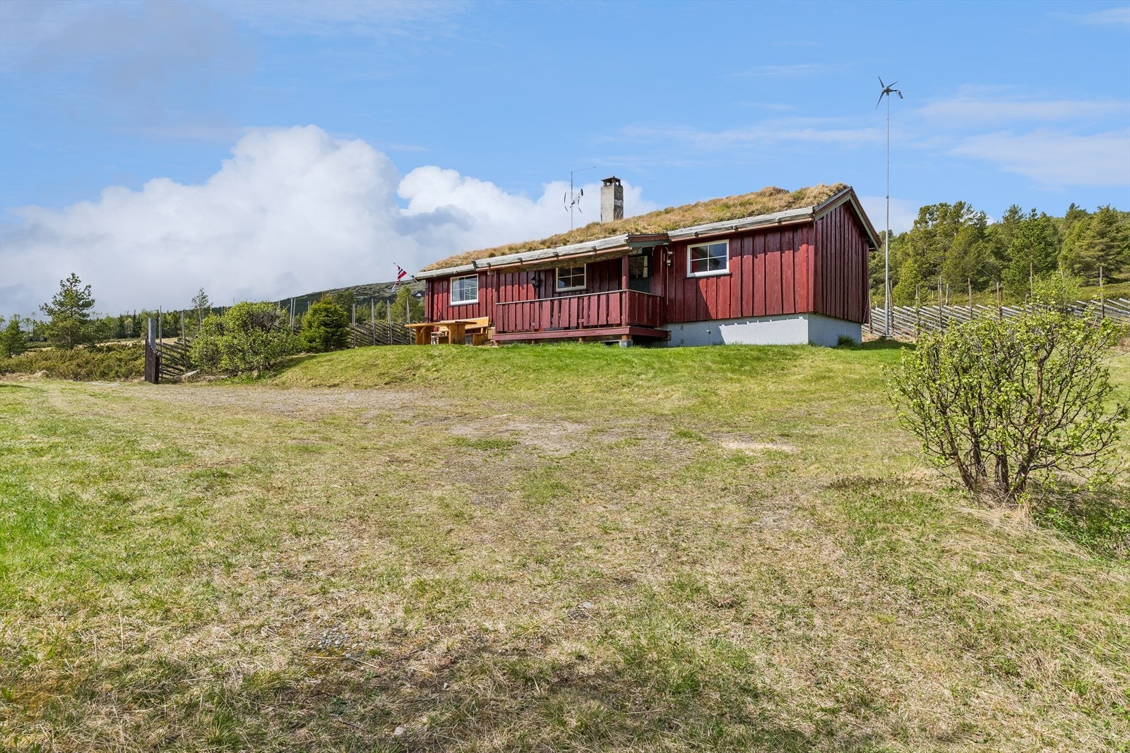 Hytta har et tradisjonelt uttrykk med torvtak og stående villmarkspanel. Galleribilde
