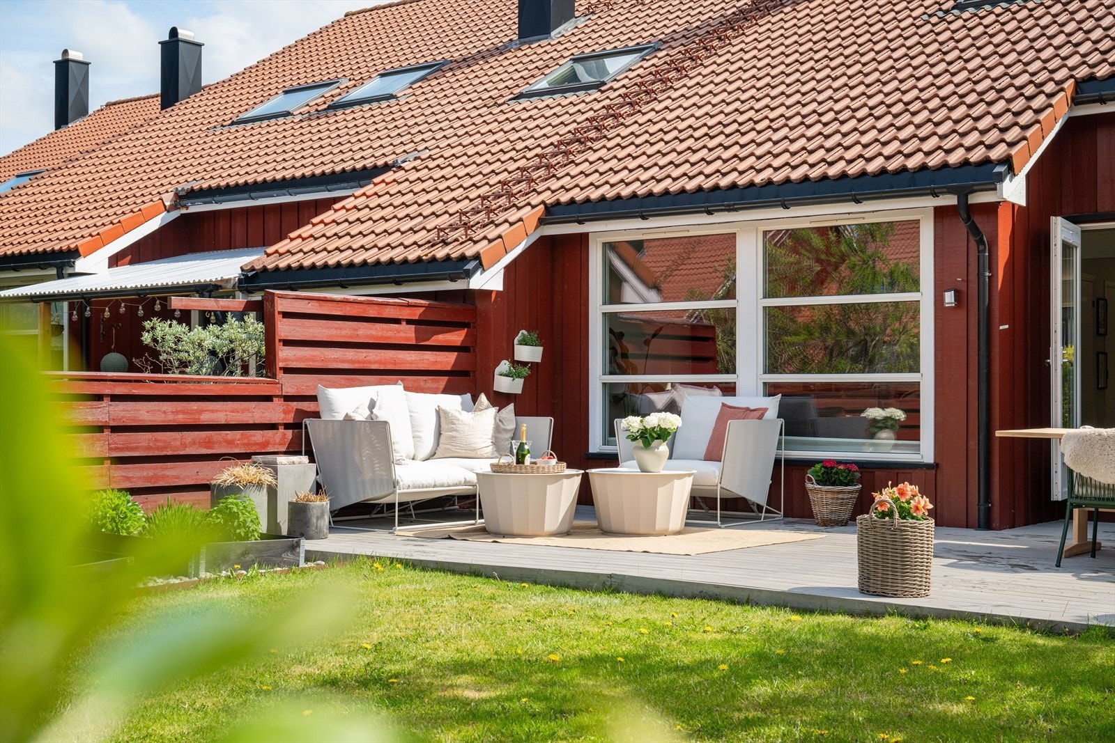 Her er det en stor platting med terrassebord, kombinert med plen og beplantning. Galleribilde