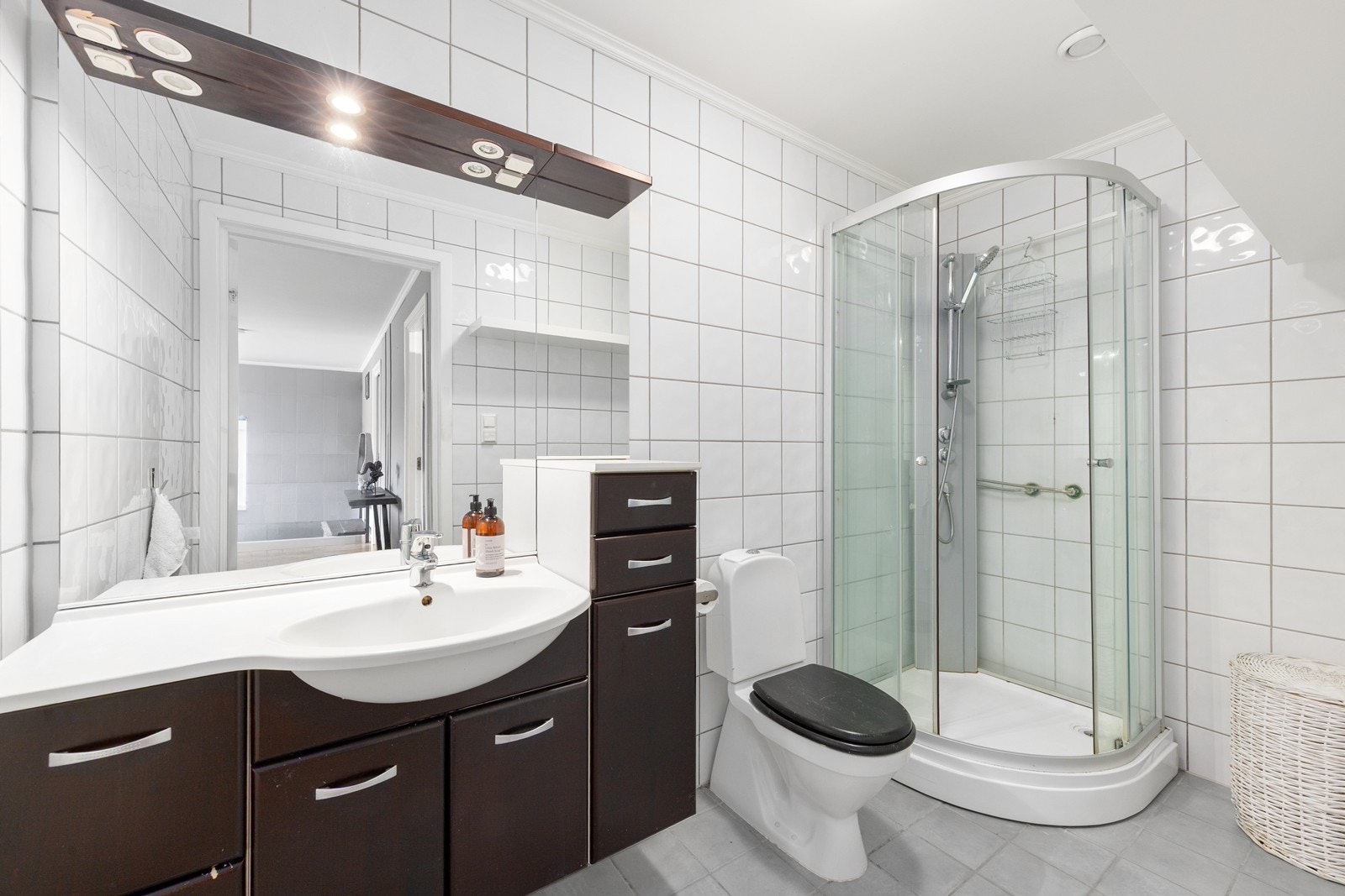 Badet er flislagt med gulvvarme og er utstyrt med innredning med nedfelt servant, dusjkabinett og toalett. Galleribilde