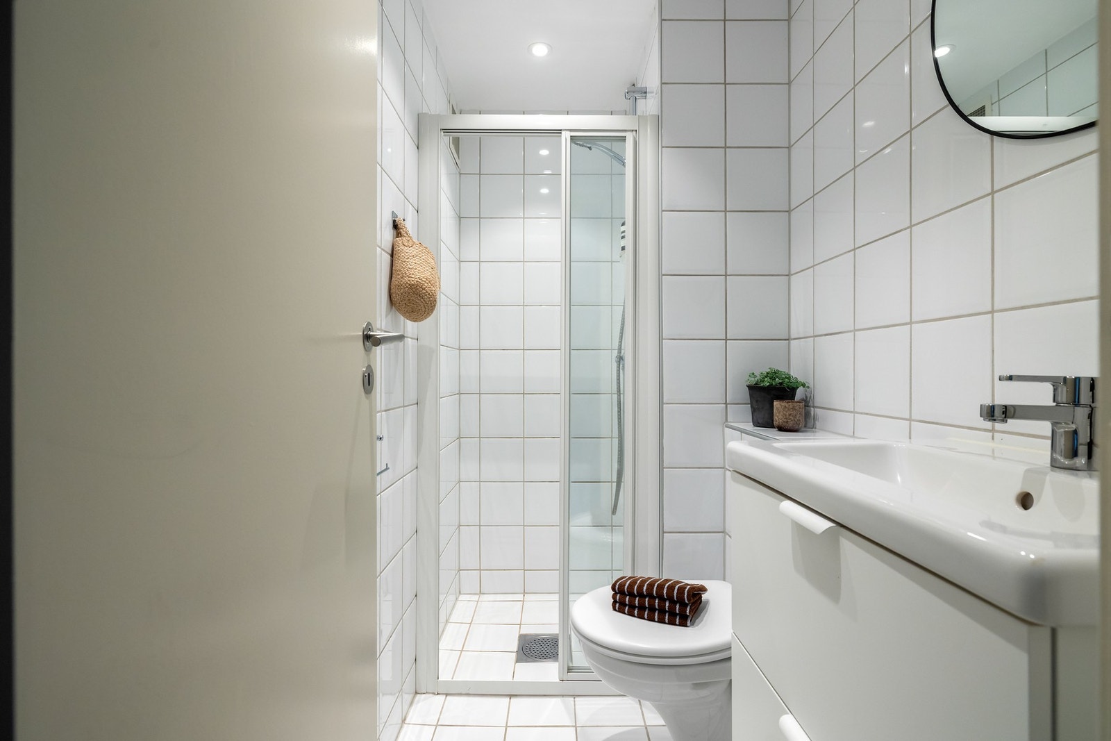 Badet med adkomst fra entréen har flislagte overflater, gulvvarme og downlights i himling Galleribilde