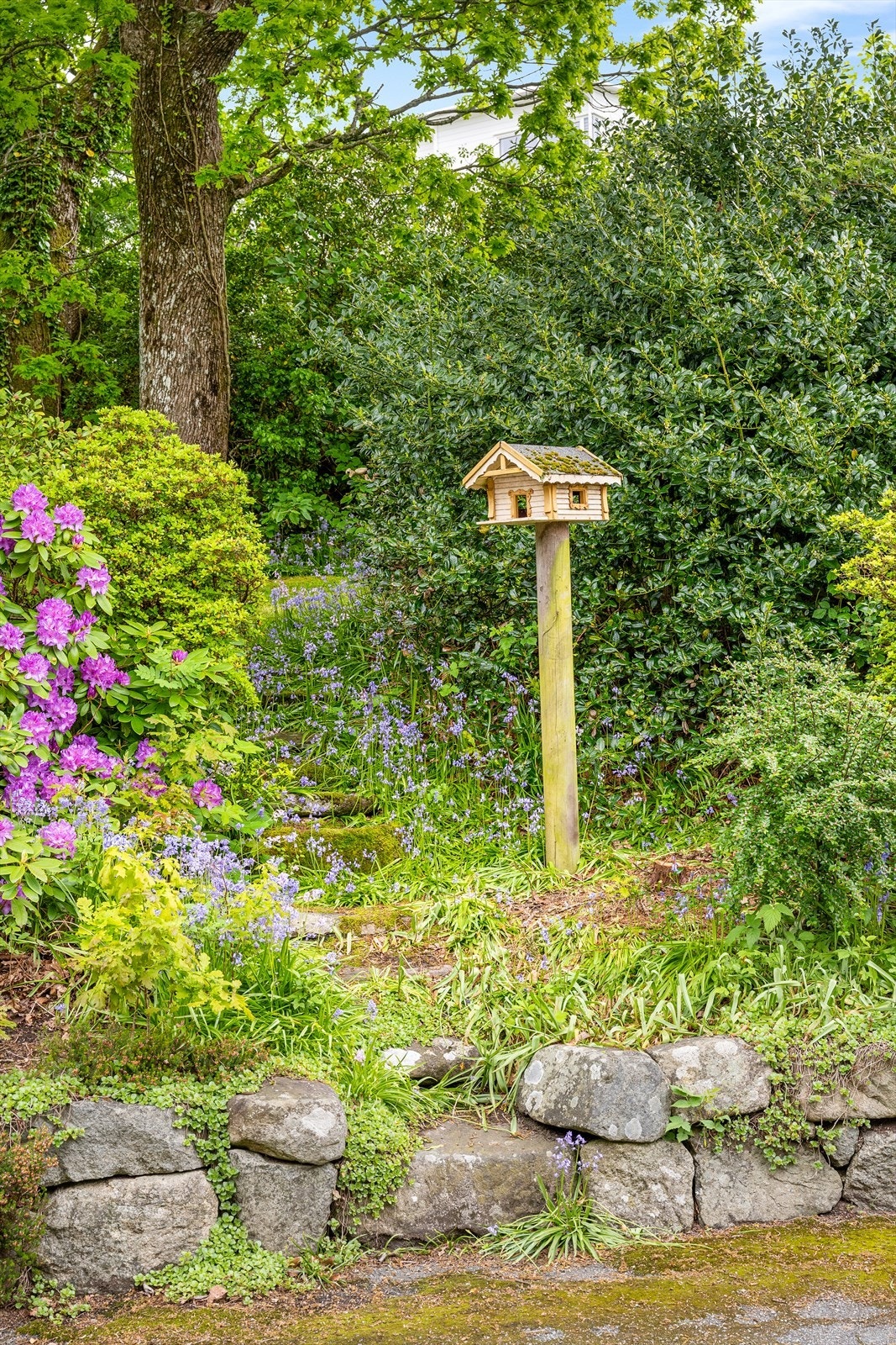 Hagen er etablert i skrånet terreng med natursteinsmurer og frodig beplantning. Galleribilde