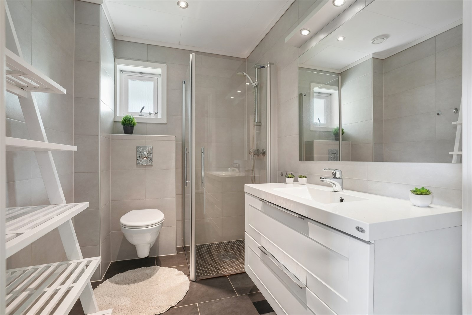 Badet i første etasje har flislagt gulv med varmekabler, vegghengt toalett og dimbare LED-spotter i taket. Galleribilde