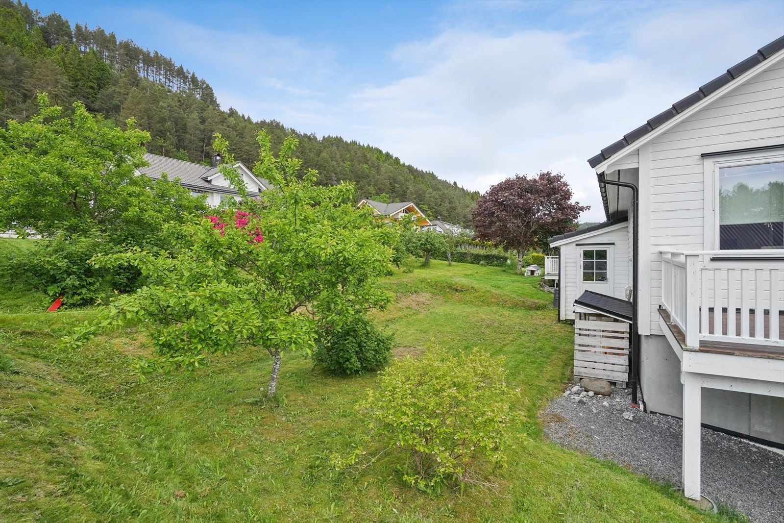 På baksiden er det en hage med plen og beplantning, samt en praktisk utebod på 5 m². Galleribilde