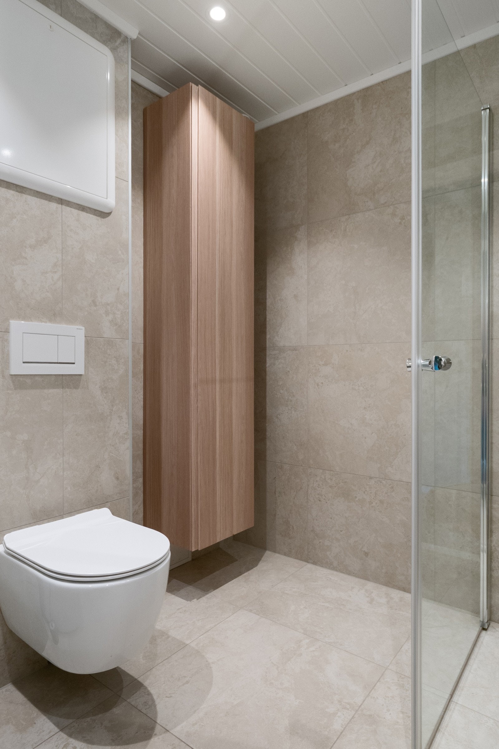 Badet er utstyrt med vegghengt toalett, dusjhjørne med glassdører, baderomsmøbel med heldekkende servantplate og opplegg for vaskemaskin. Galleribilde