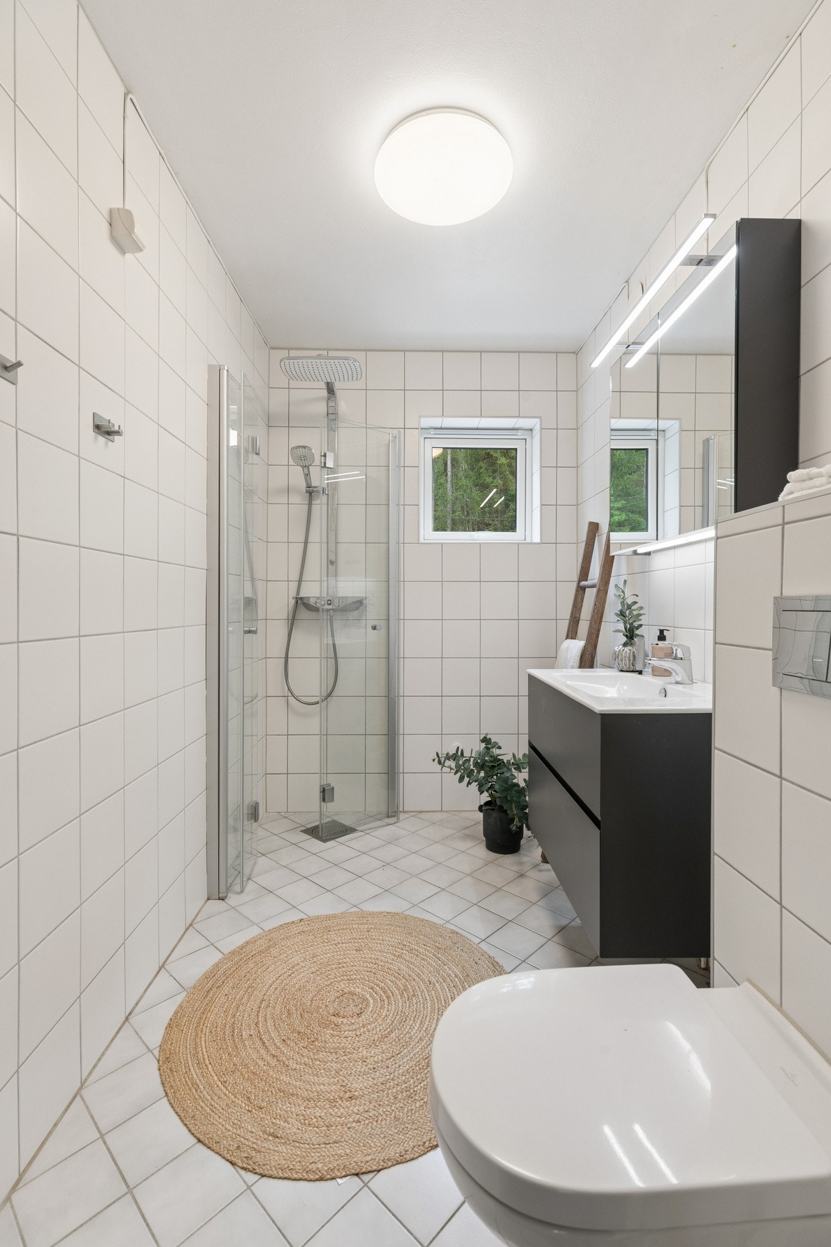 Et lyst og delikat baderom innredet med dusj, baderomsinnredning og toalett. Galleribilde
